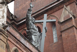 A statue of a person holding a cross in front of a church