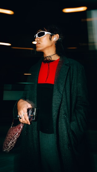 A woman in a black coat and sunglasses holding a purse
