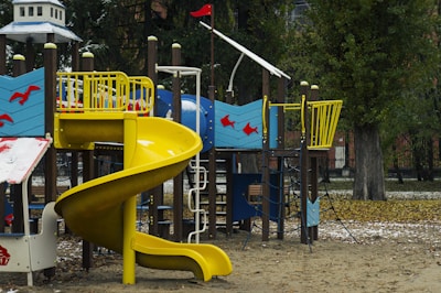 A playground with a yellow slide in the middle of it