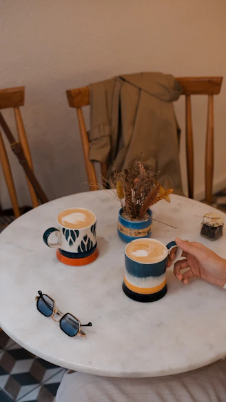 A person sitting at a table with two cups of coffee