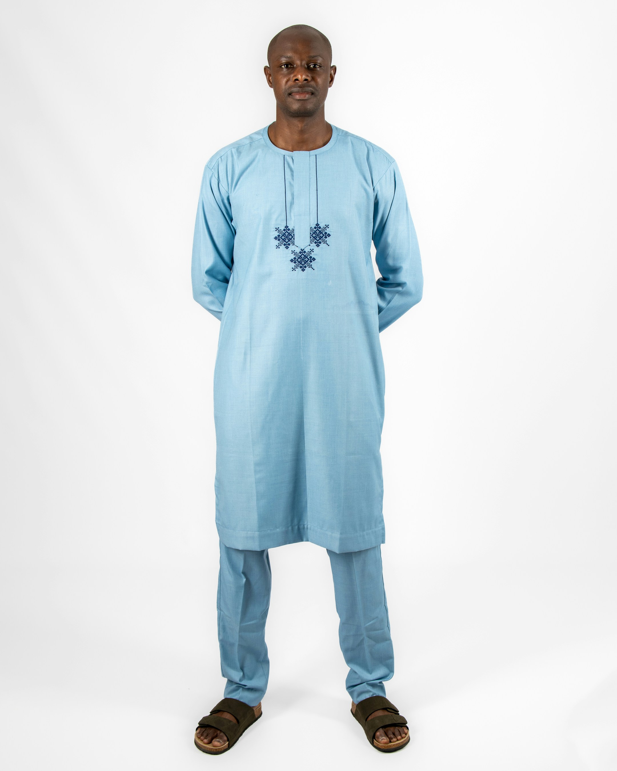 A man in a blue outfit standing in front of a white background