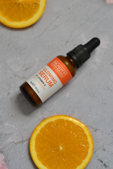 A bottle of vitamin oil sitting on top of an orange