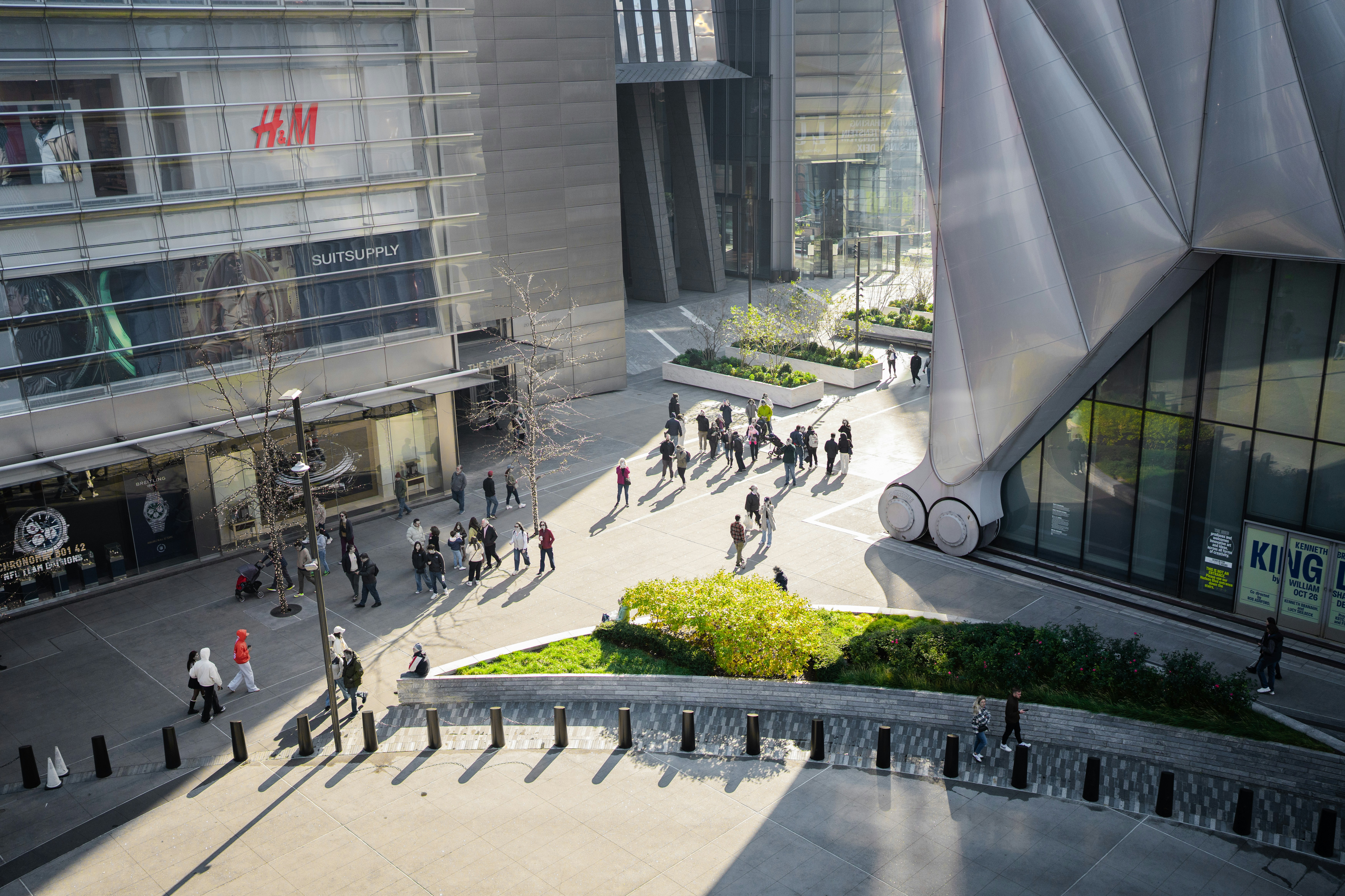 A group of people walking down a street next to tall buildings