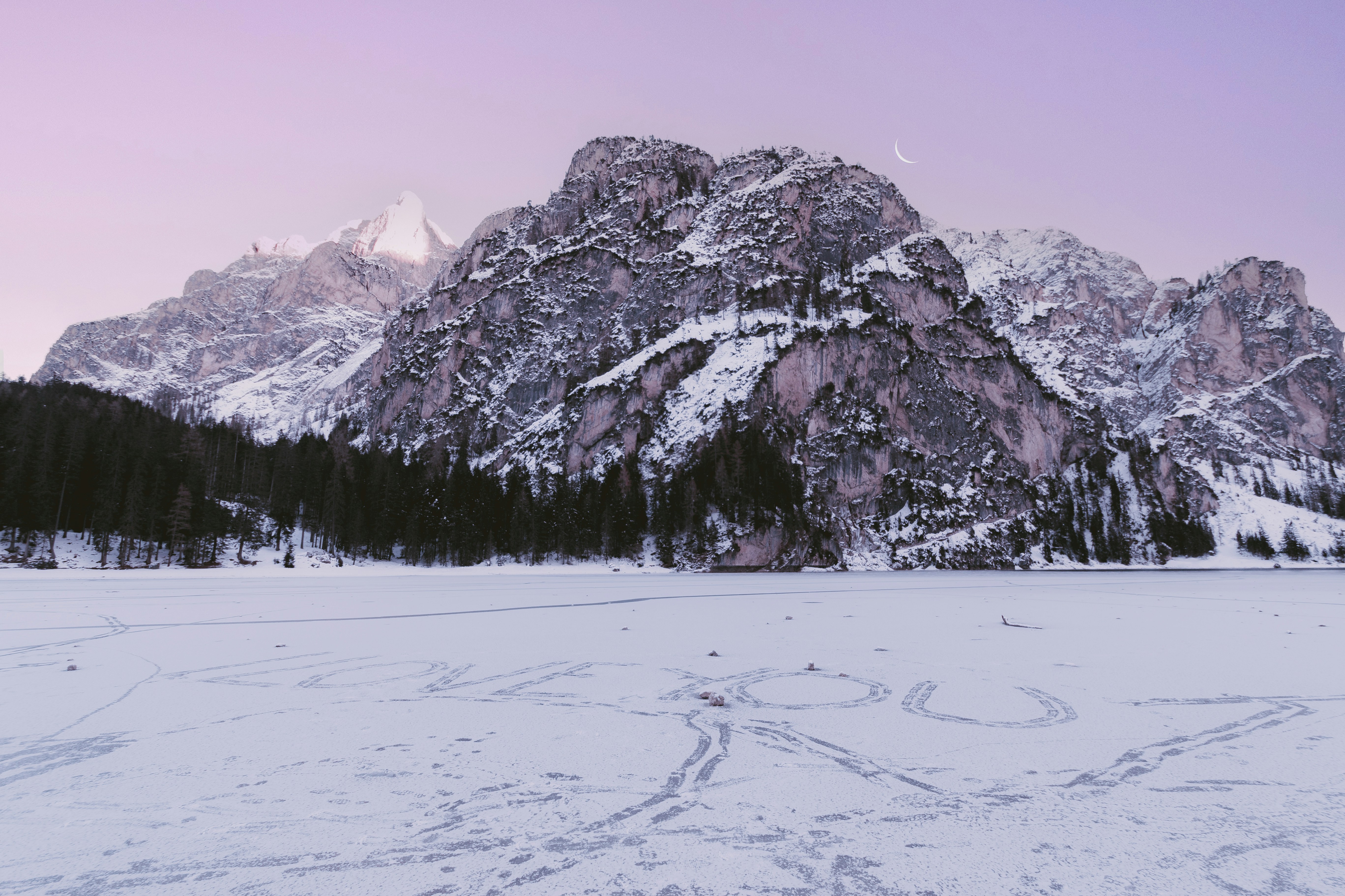 A snow covered field with a mountain in the background