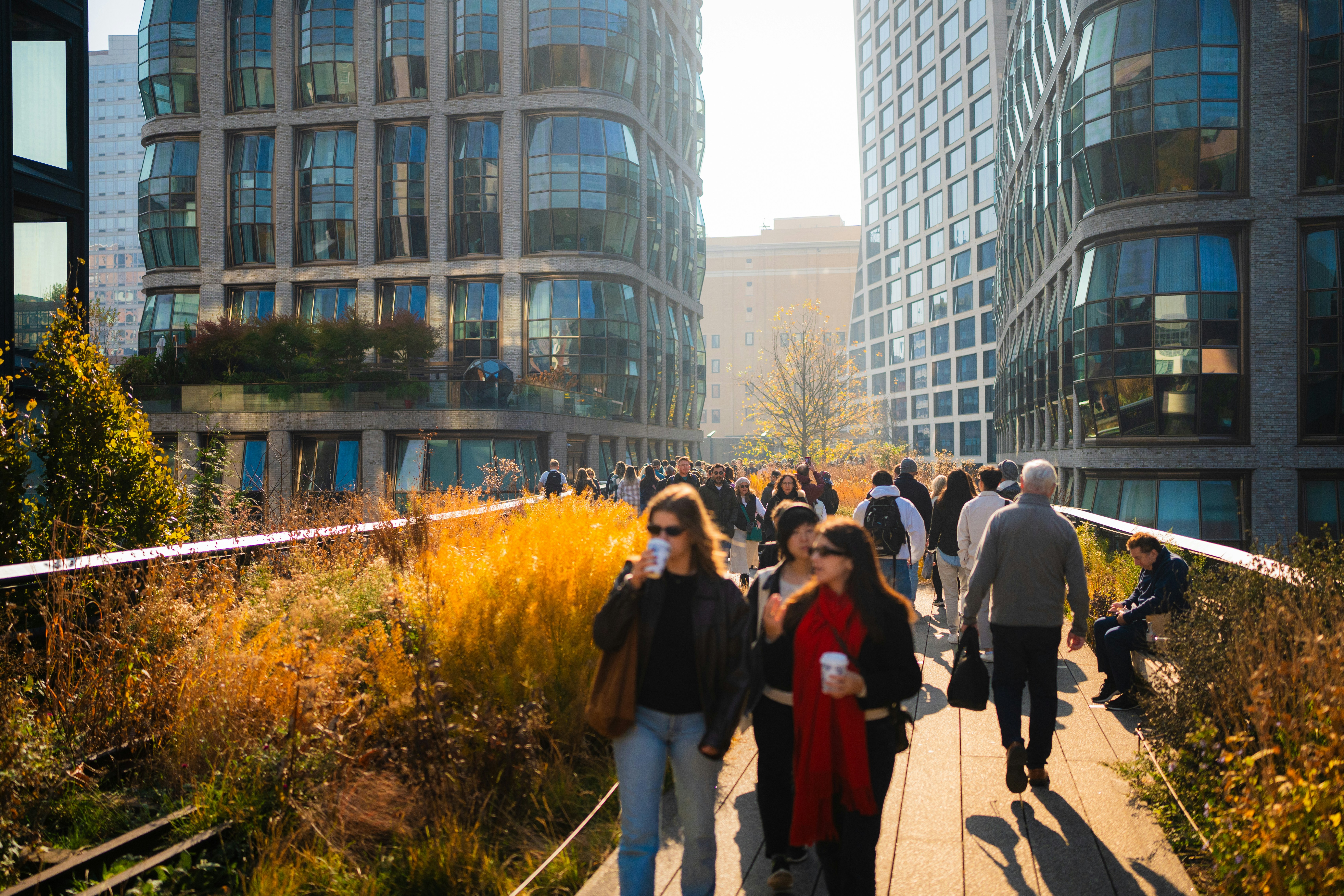 A group of people walking down a sidewalk next to tall buildings