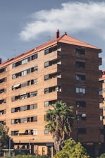 A tall brown building sitting next to a lush green park