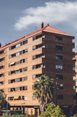 A tall brown building sitting next to a lush green park