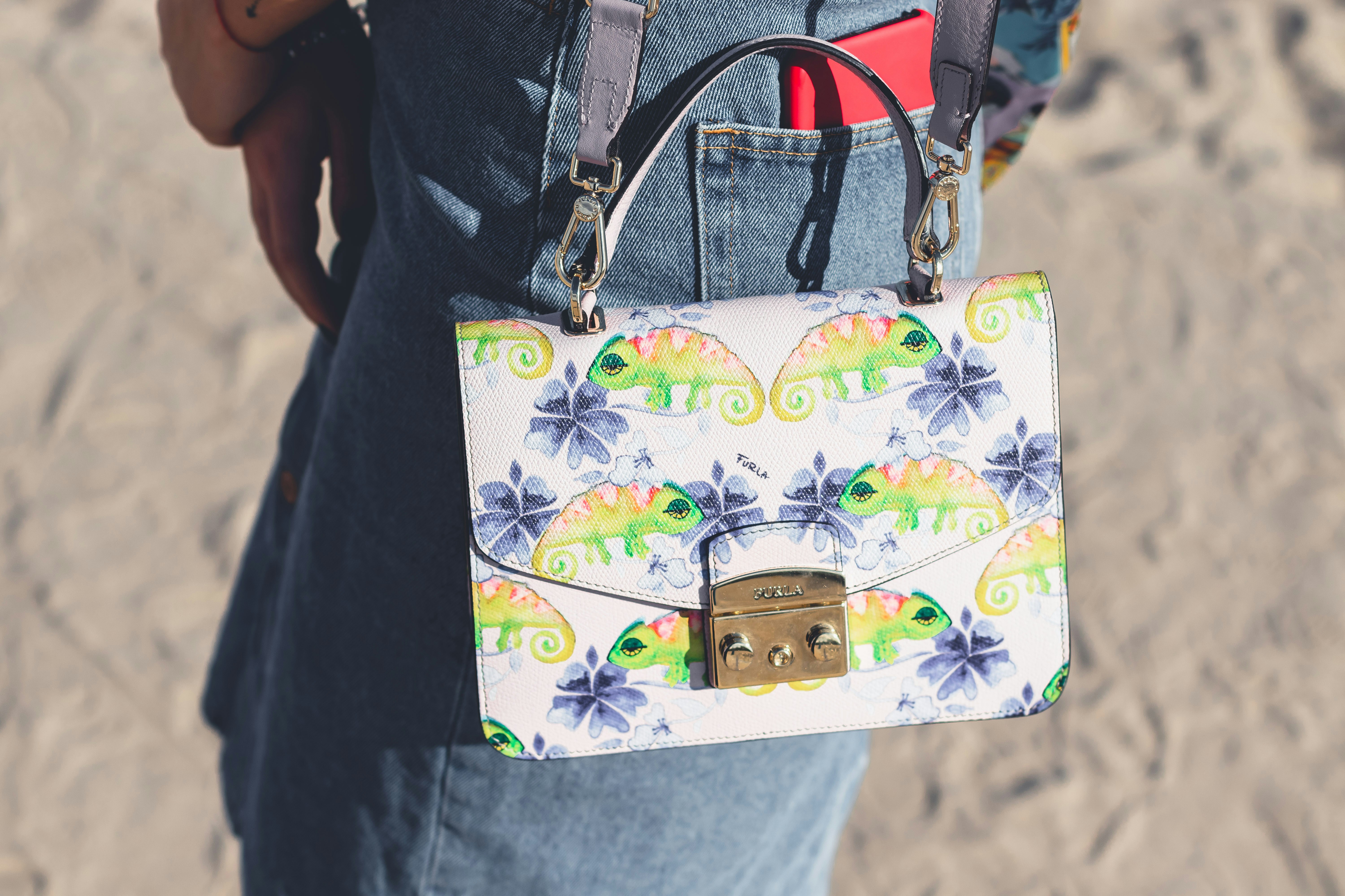 A woman holding a white purse on top of a sandy beach