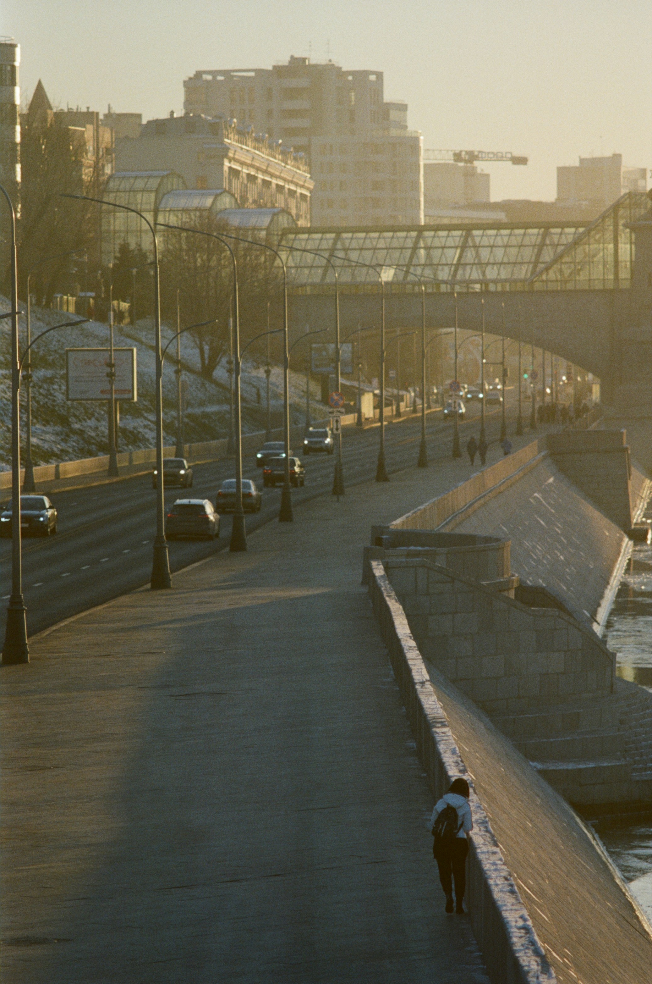 A person walking on a sidewalk next to a body of water