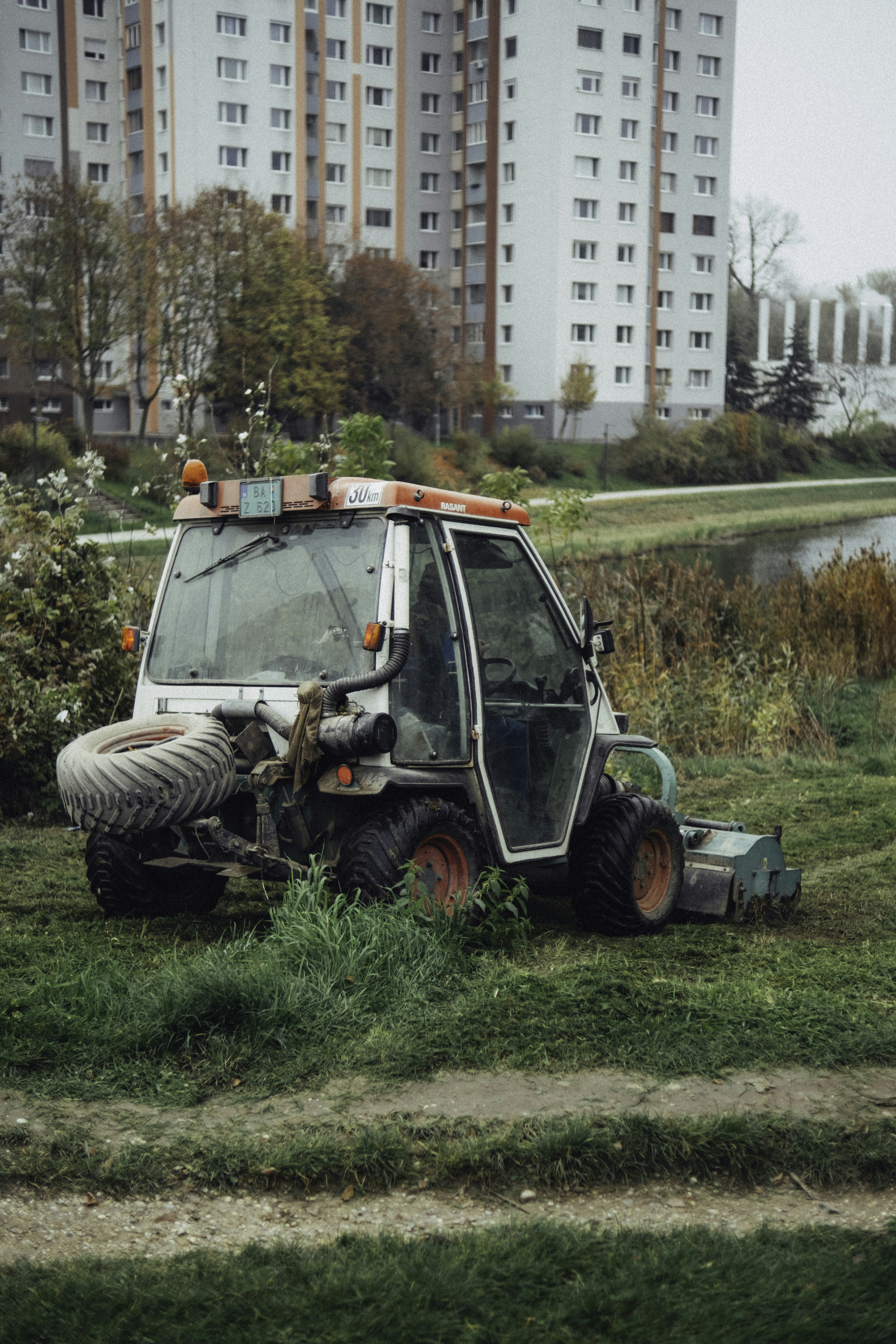 A tractor is parked in the grass near a body of water