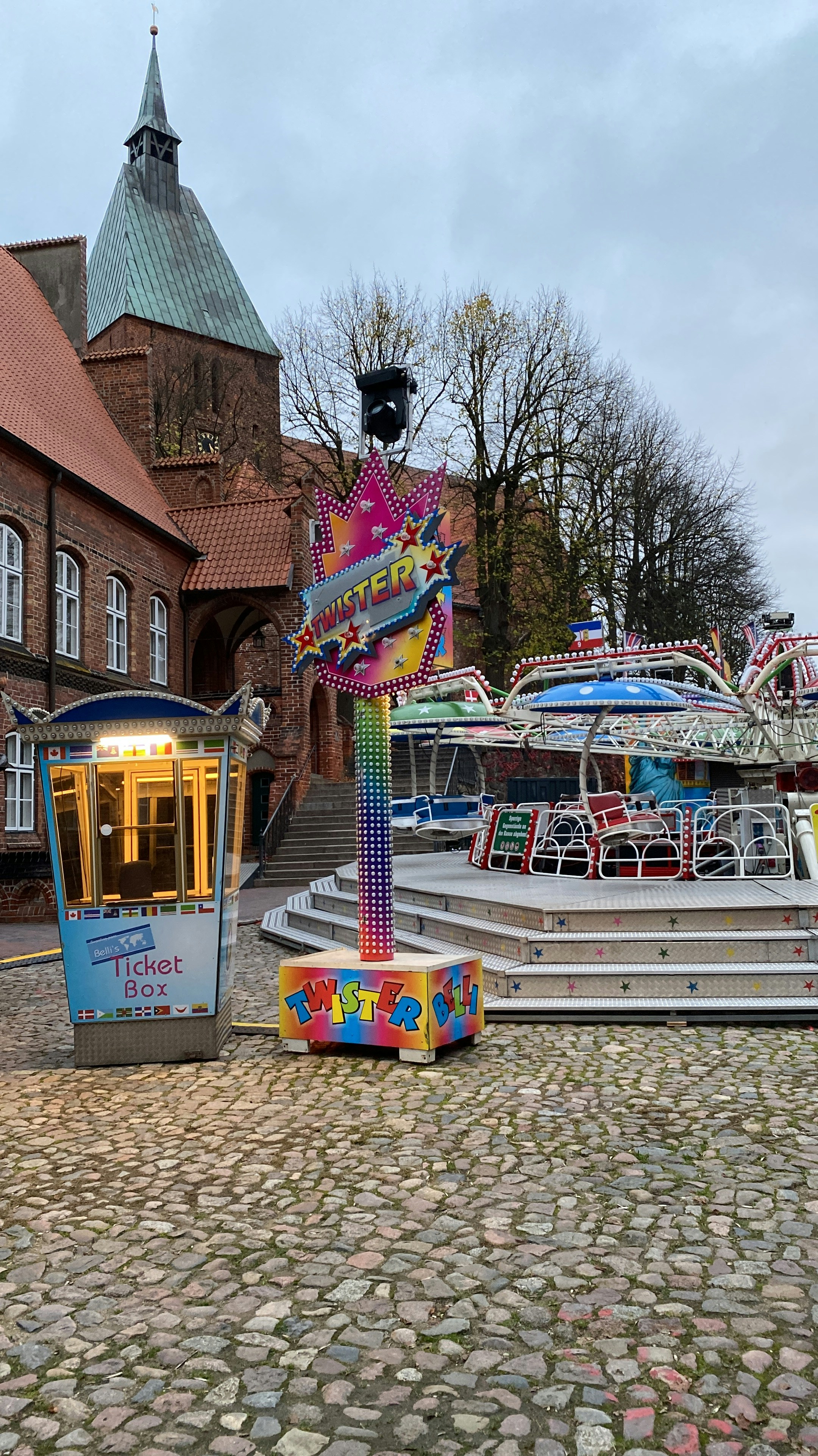 A colorful carnival ride sitting on top of a cobblestone road