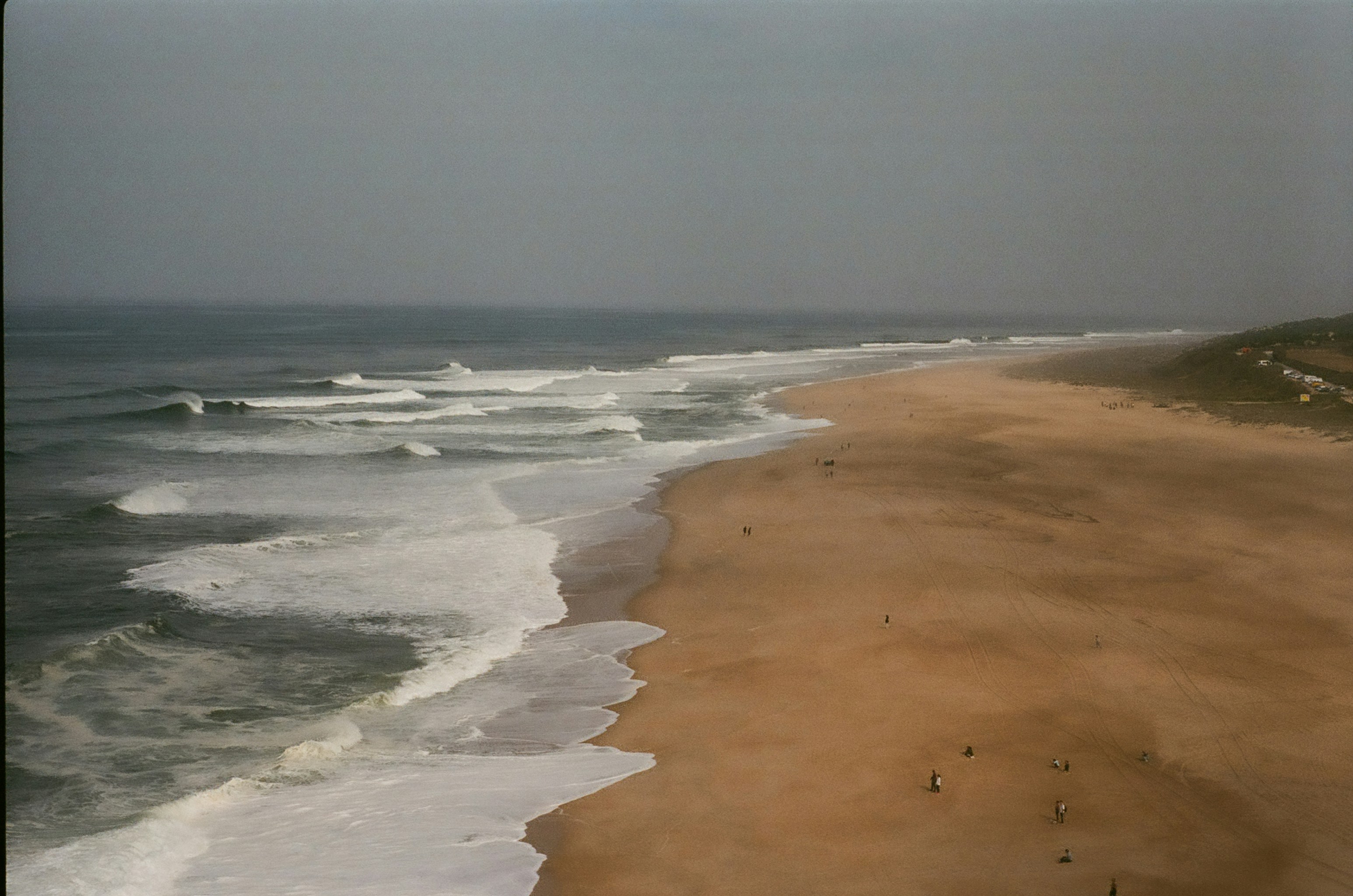 A sandy beach next to the ocean under a cloudy sky