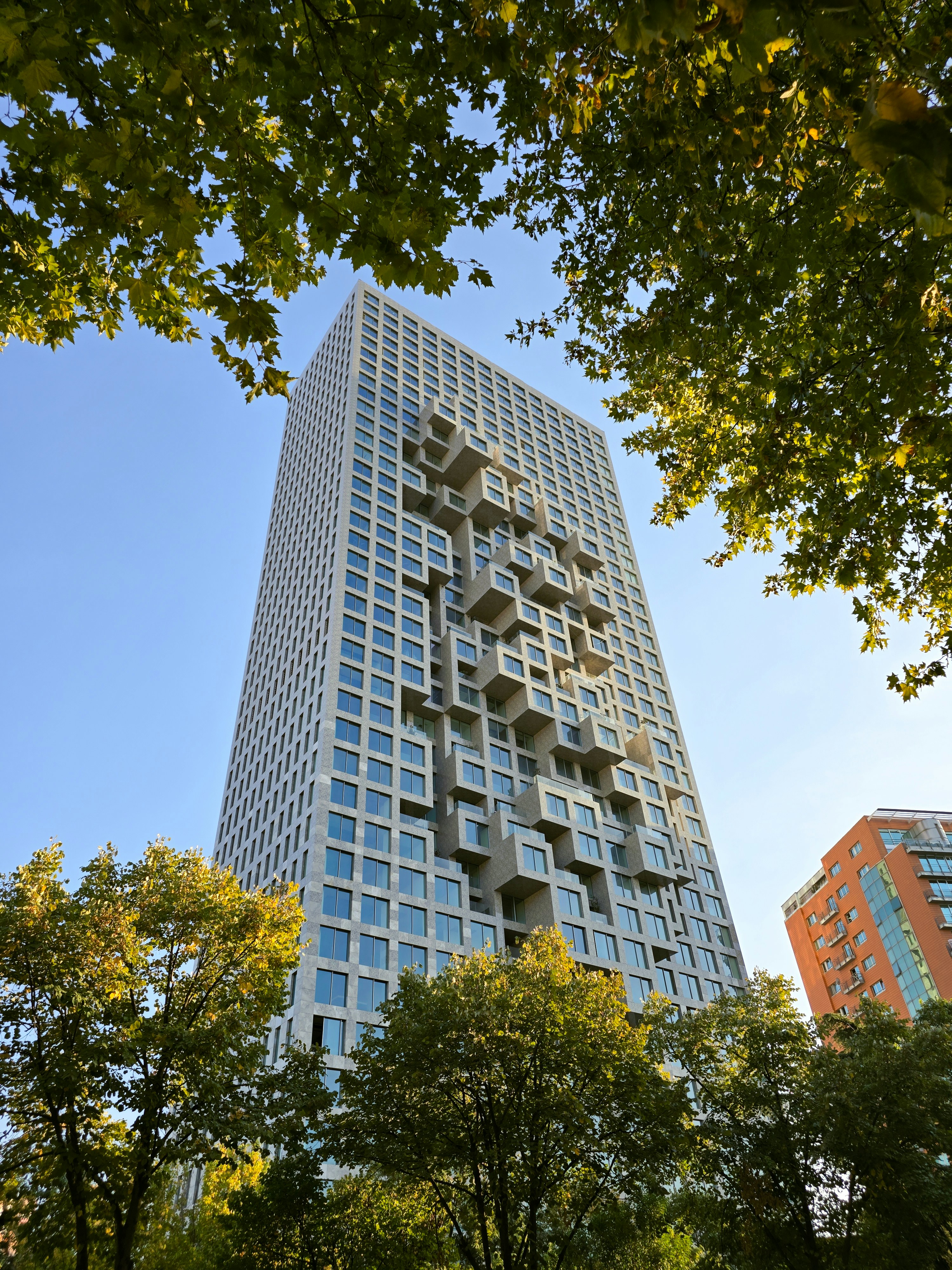 Ein hohes Gebäude mit vielen Fenstern mitten in einem Park