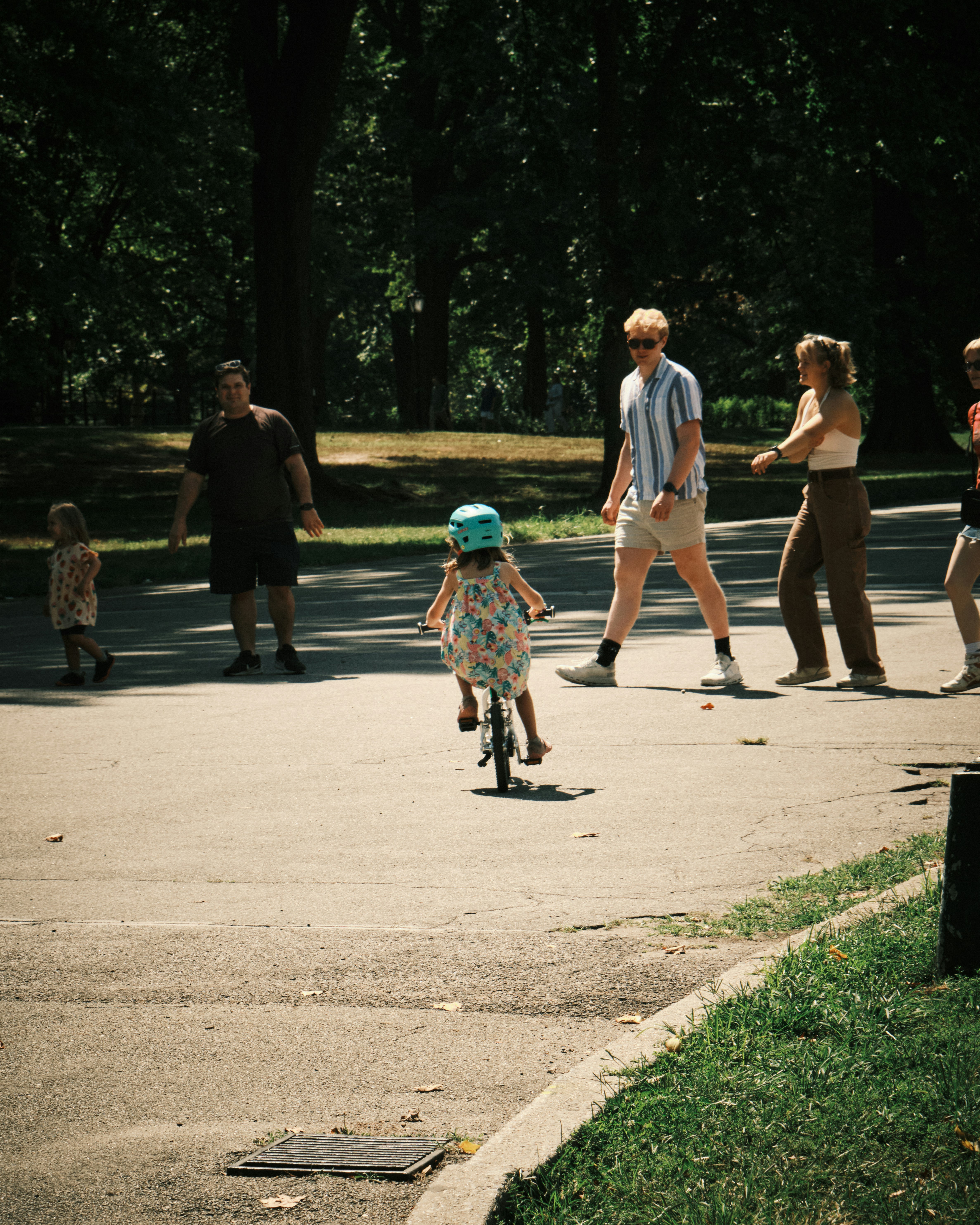 A group of people walking and riding bikes in a park