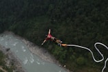 A man is parasailing over a river in the mountains