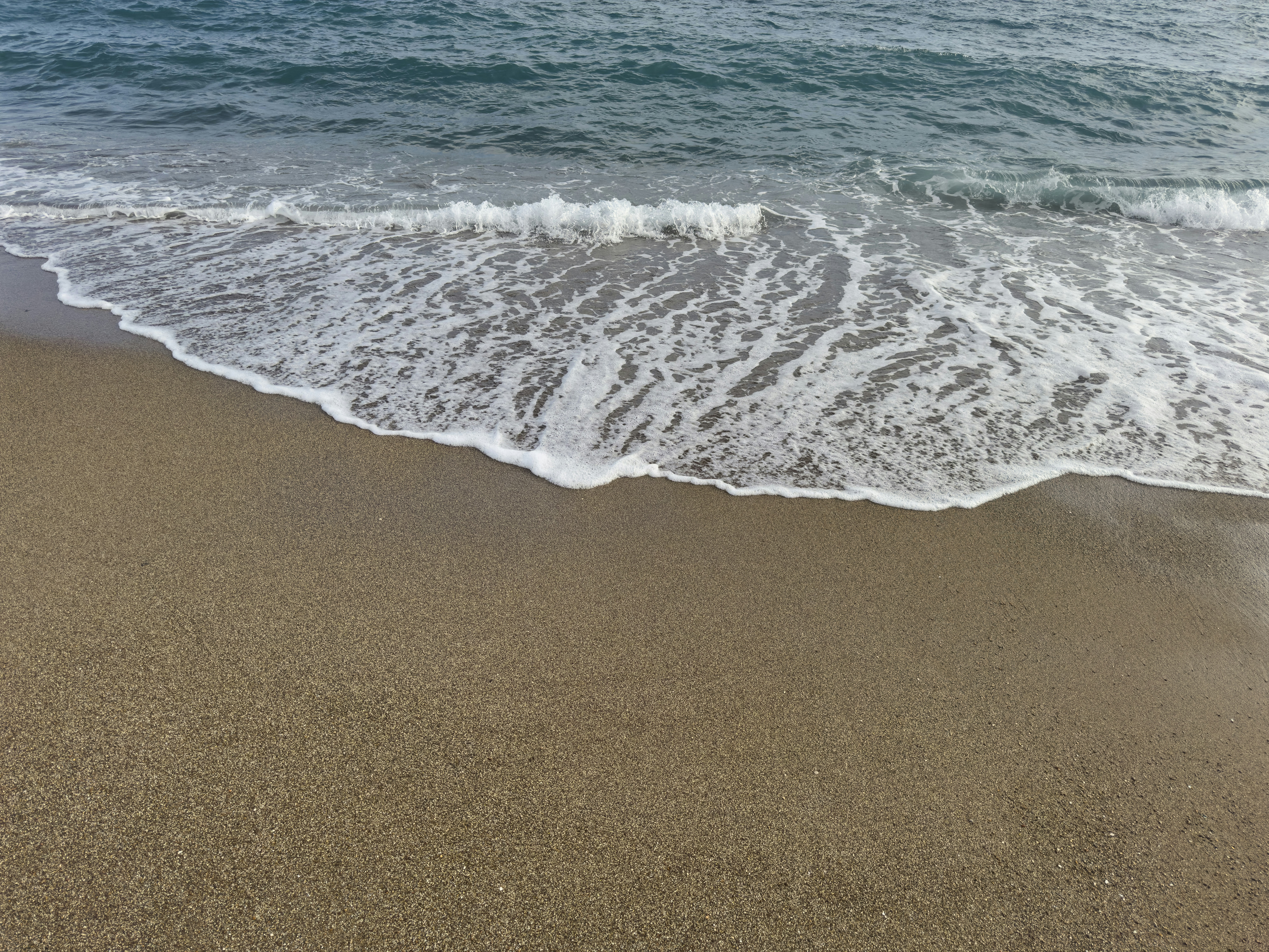 A sandy beach with waves coming in to shore