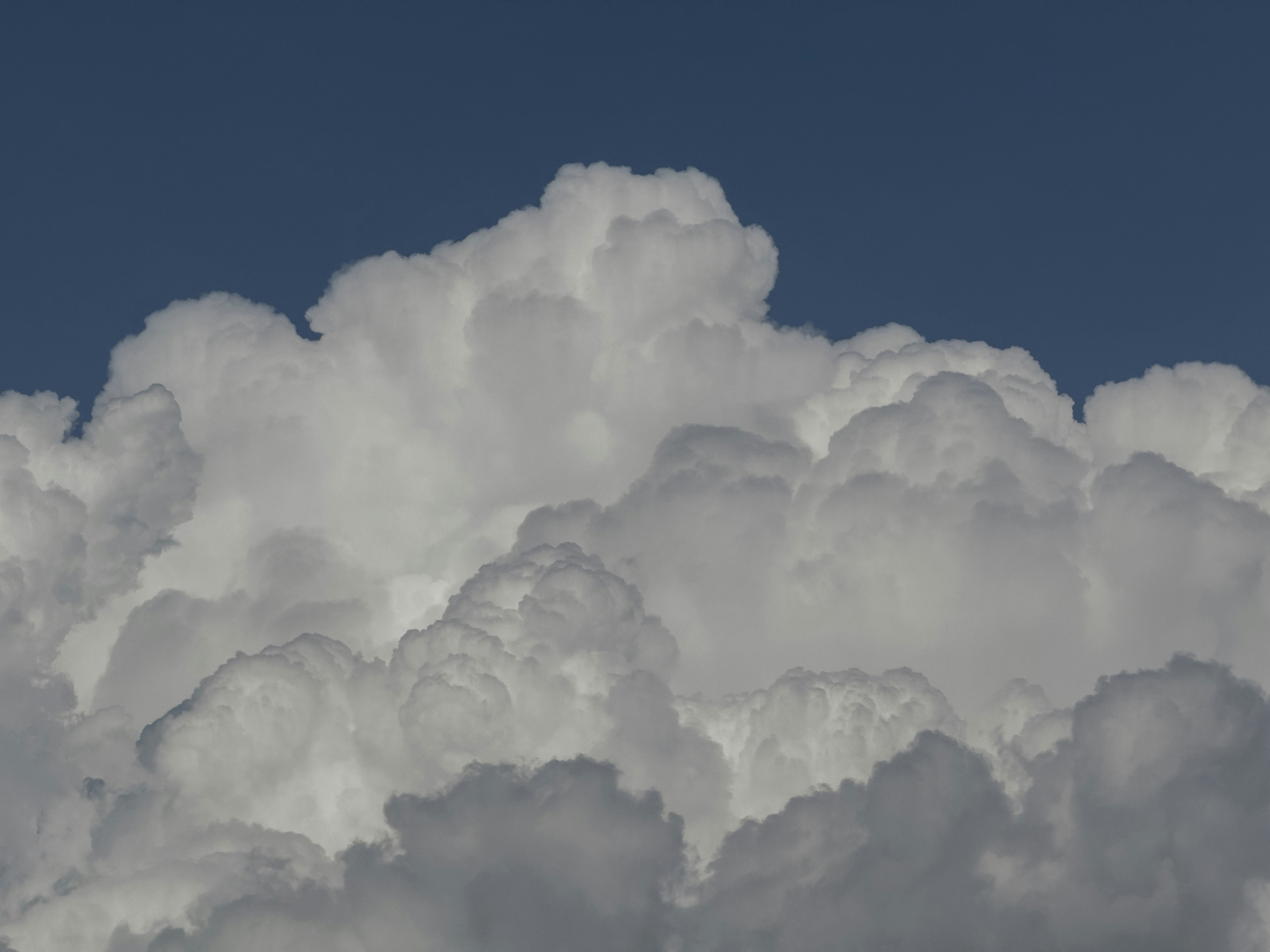 A plane flying through a cloud filled sky