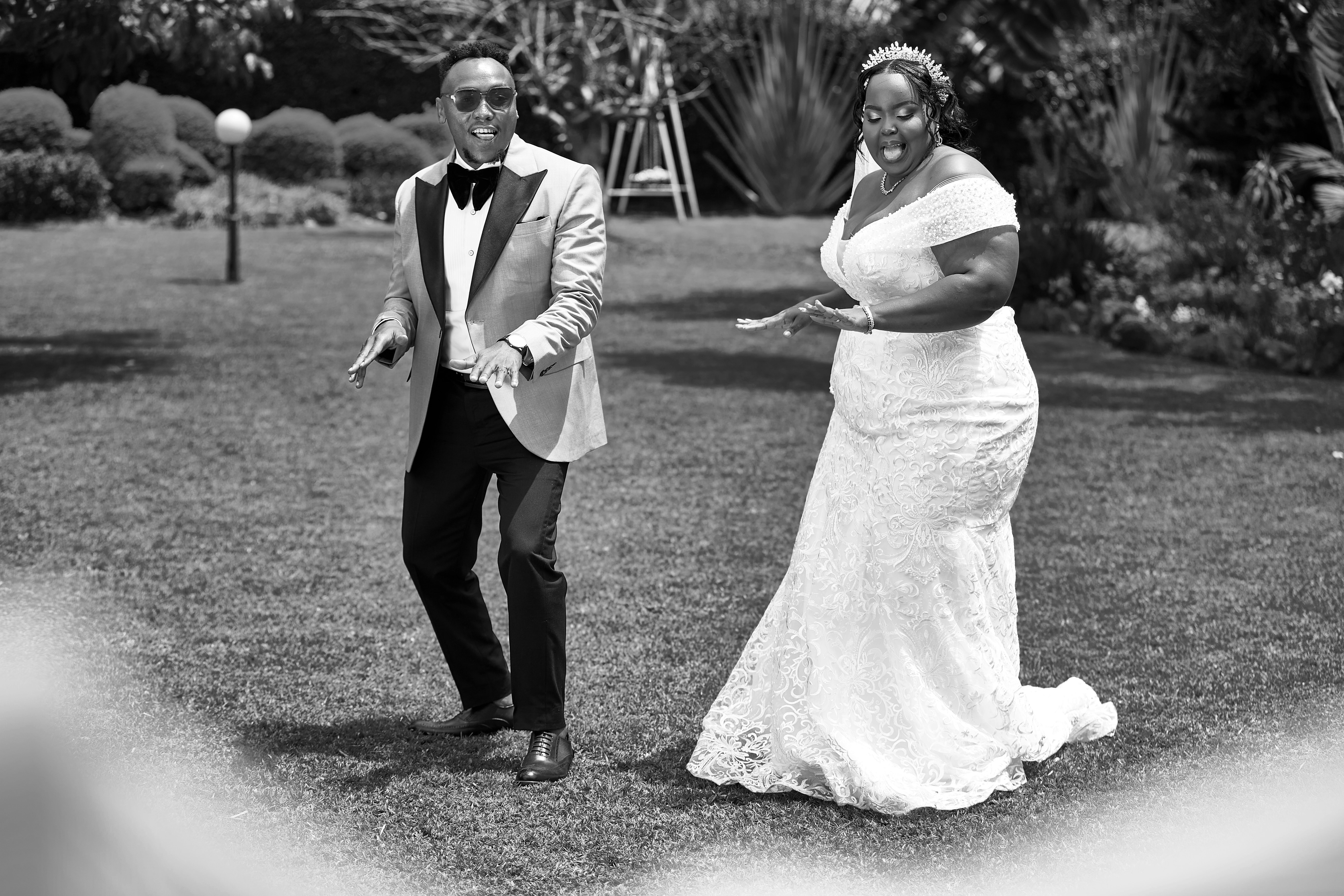 A bride and groom dance together on a green lawn.