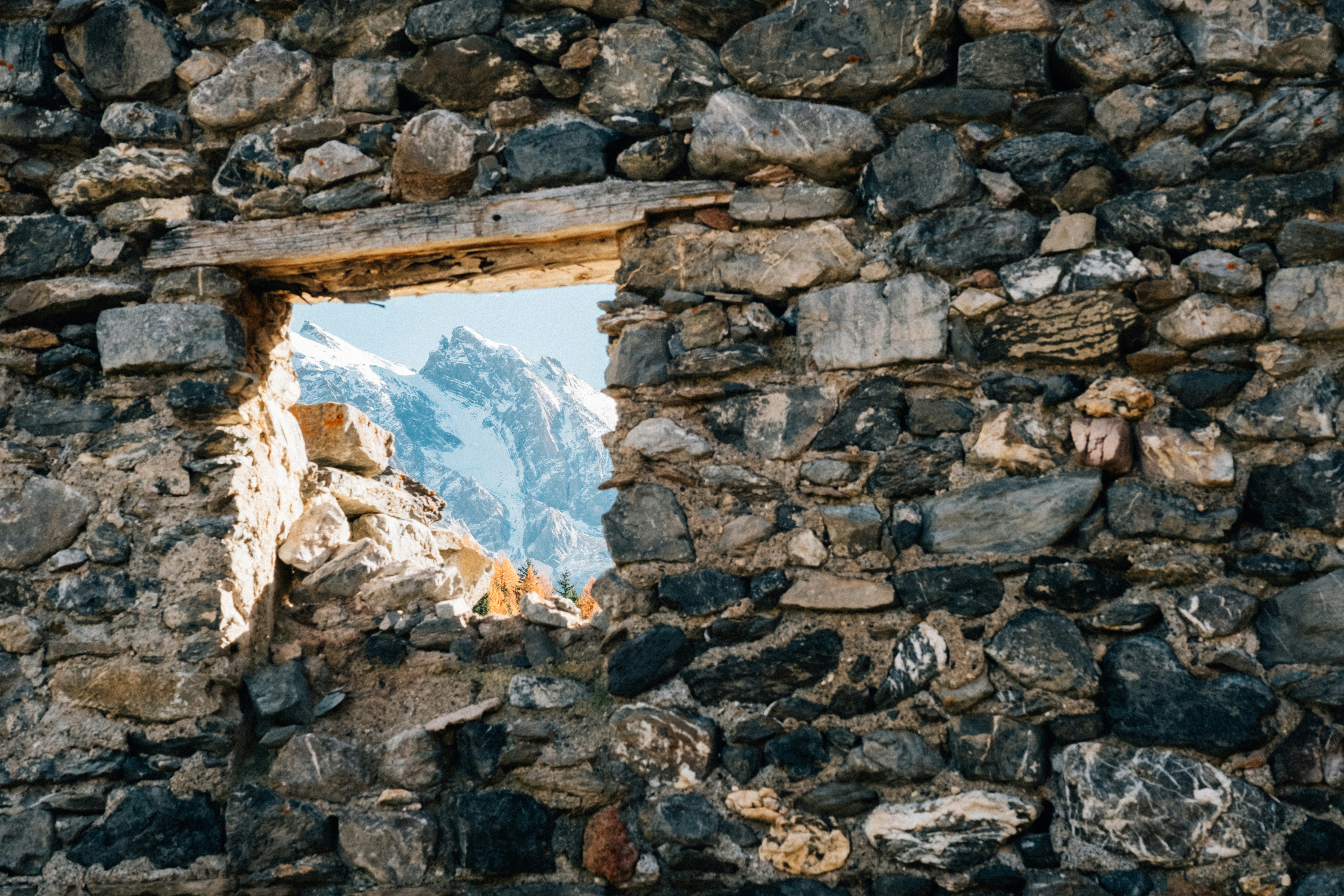 A window in a stone wall with a mountain in the background