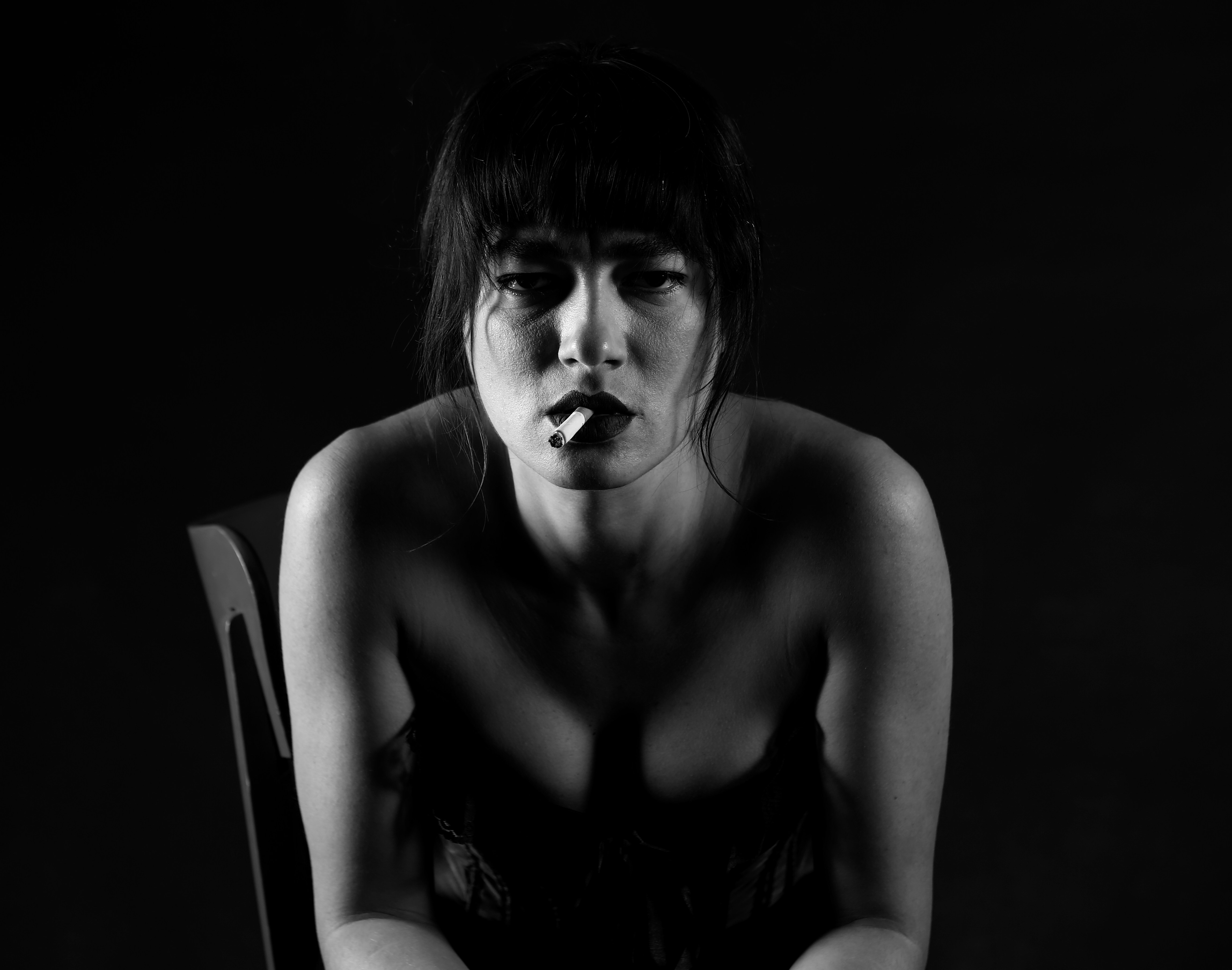A black and white photo of a woman sitting on a chair