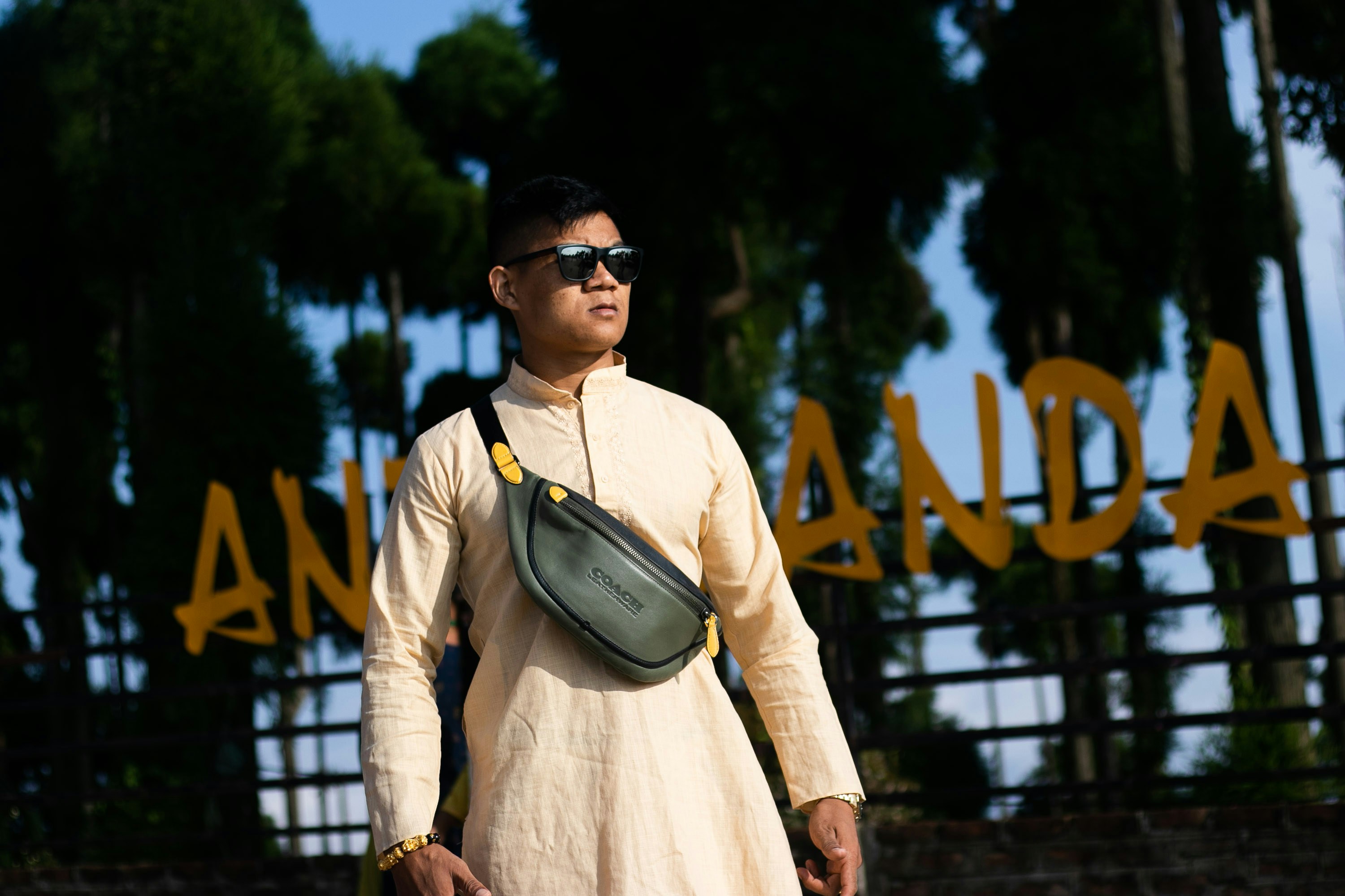 A man in a white dress holding a green bag