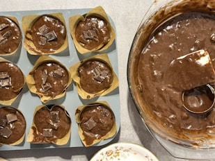 A pan filled with chocolate cupcakes next to a pan of cupcakes