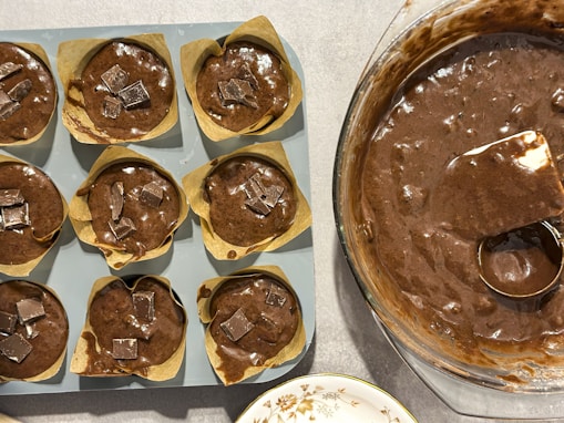 A pan filled with chocolate cupcakes next to a pan of cupcakes