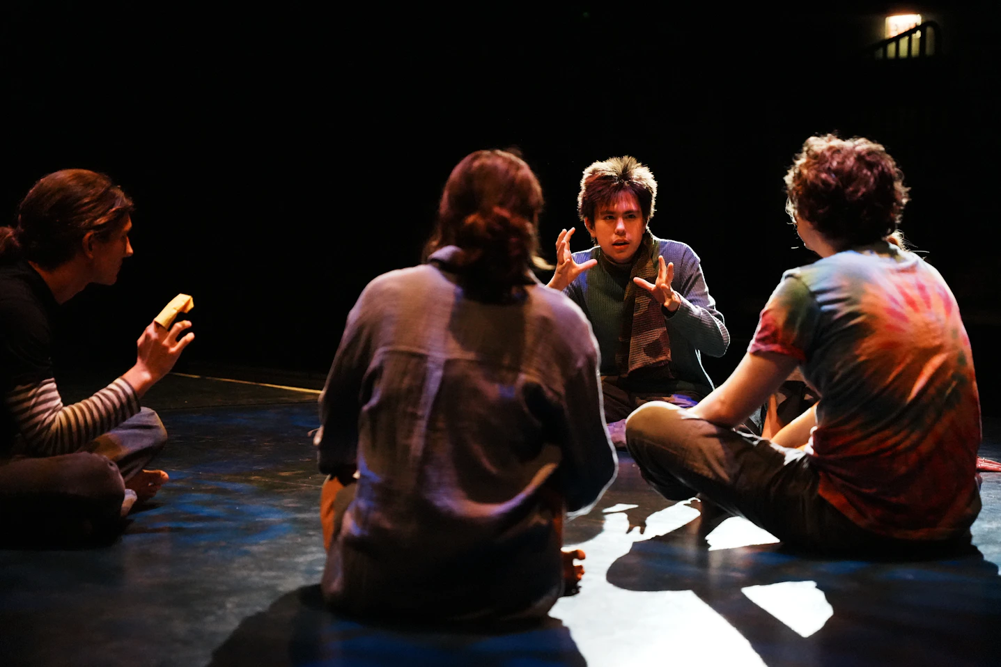 A group of people sitting on the floor talking