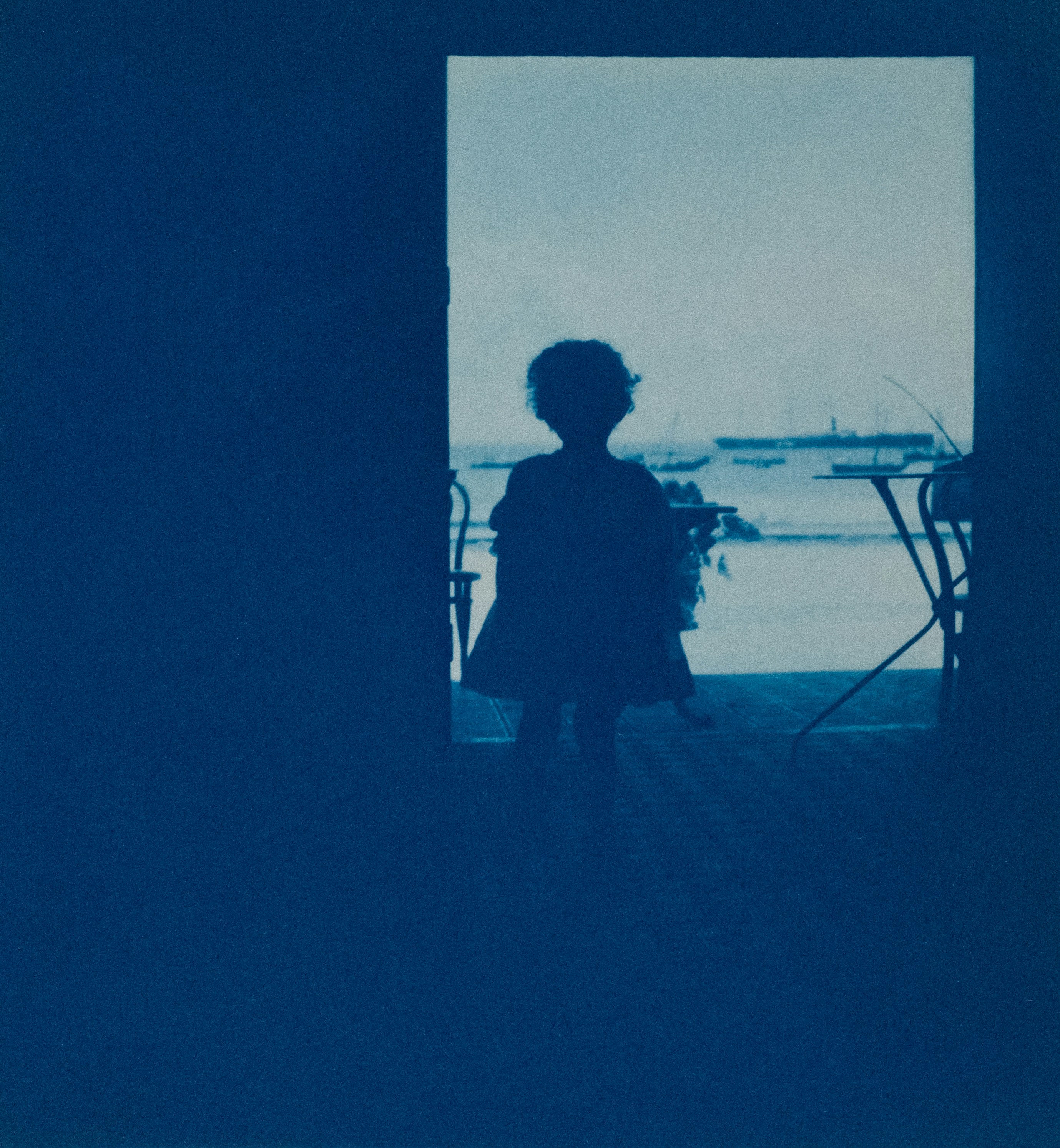 Silhouette of a child looking out at boats