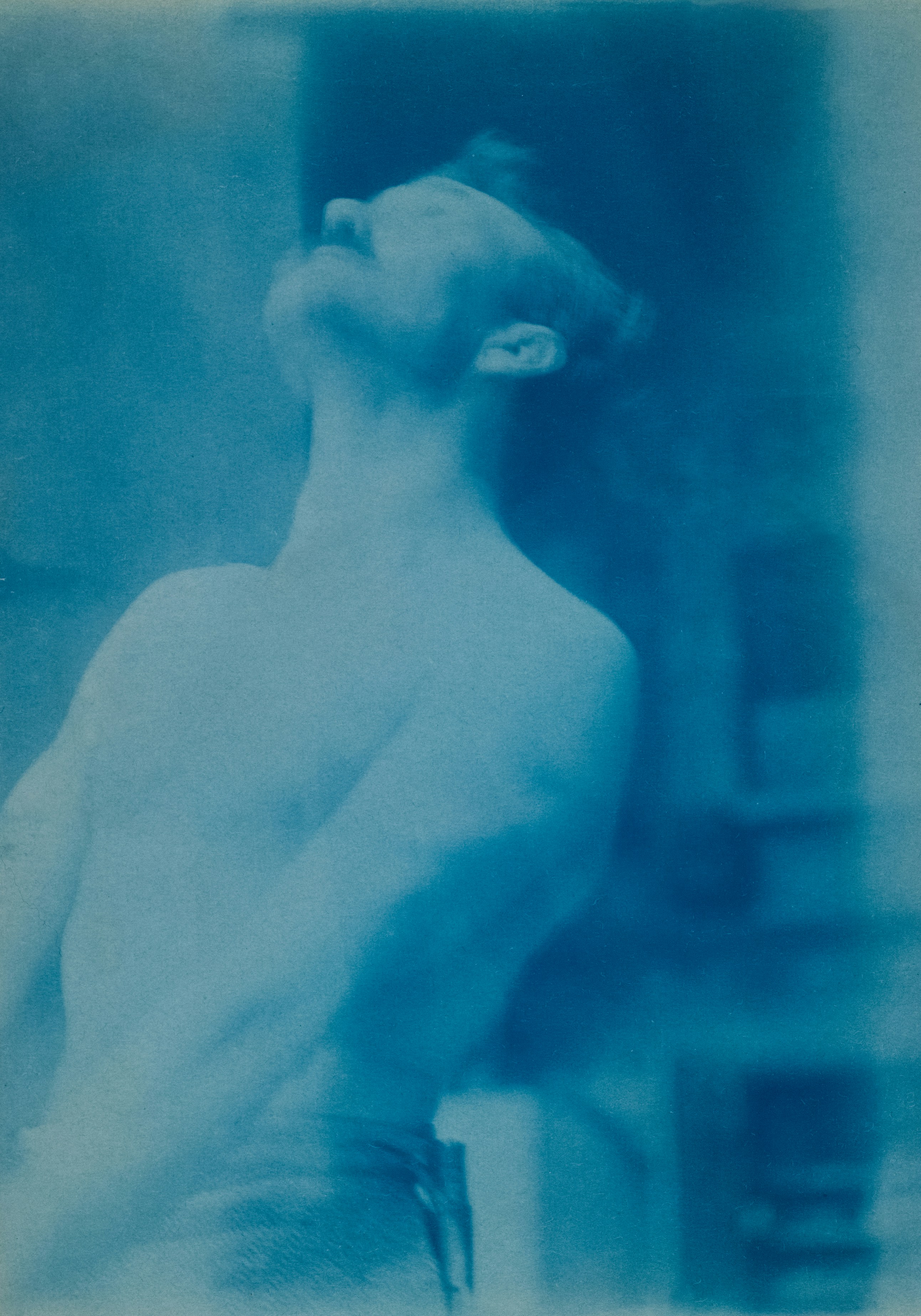 A man looks upwards, his torso is bare.