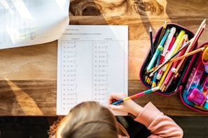 A little girl sitting at a table with a bag of pencils
