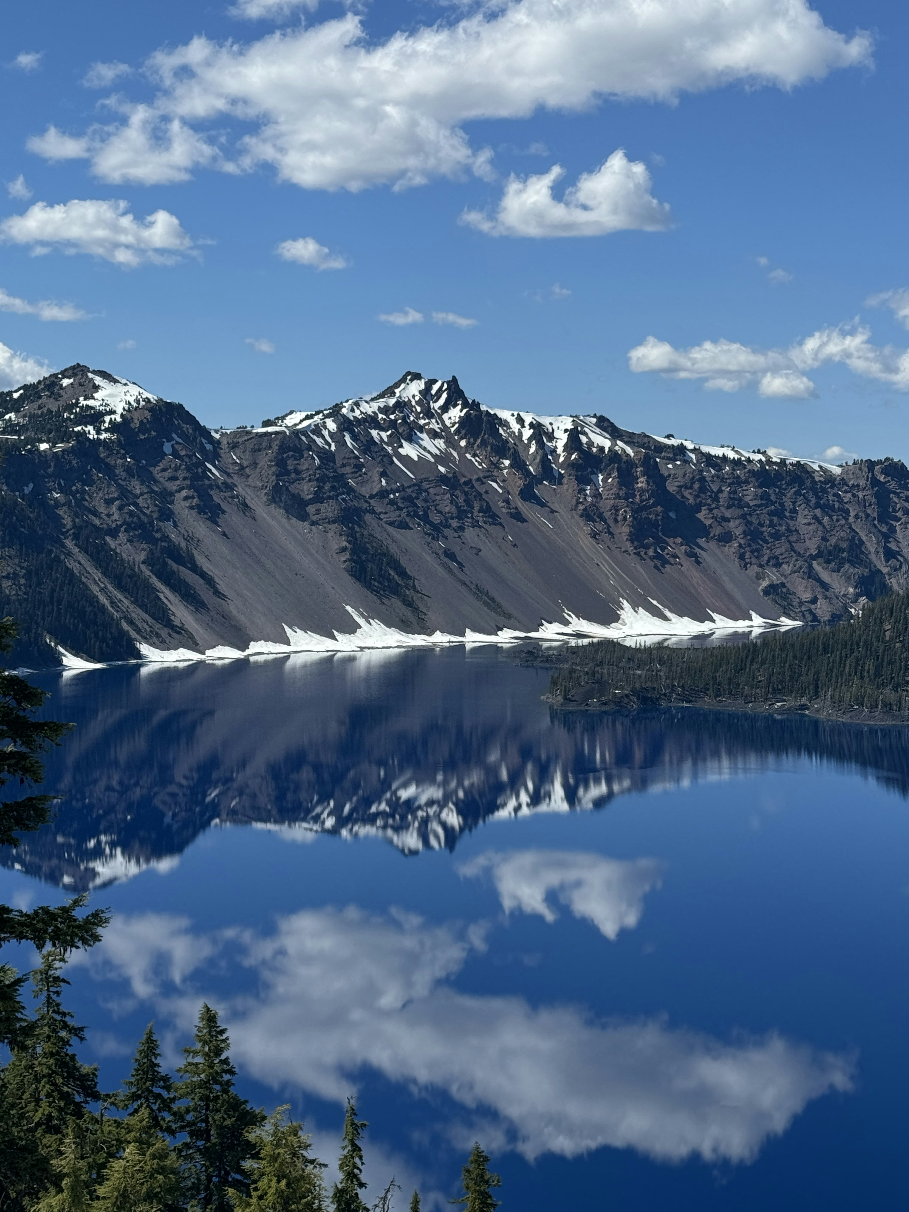 Ein See, umgeben von Bergen und Bäumen unter blauem Himmel