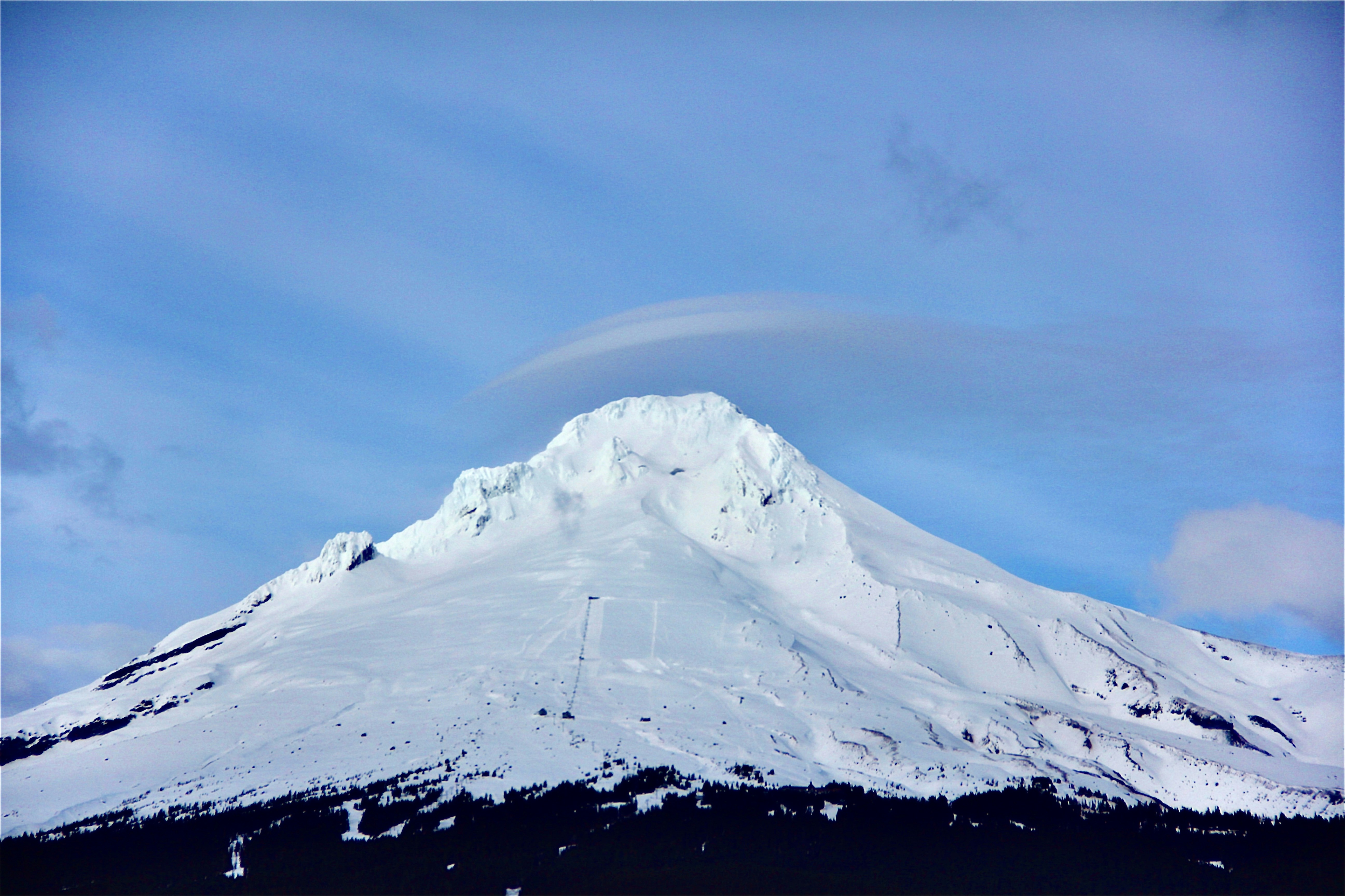 Ein schneebedeckter Berg mit einer Wolke am Himmel