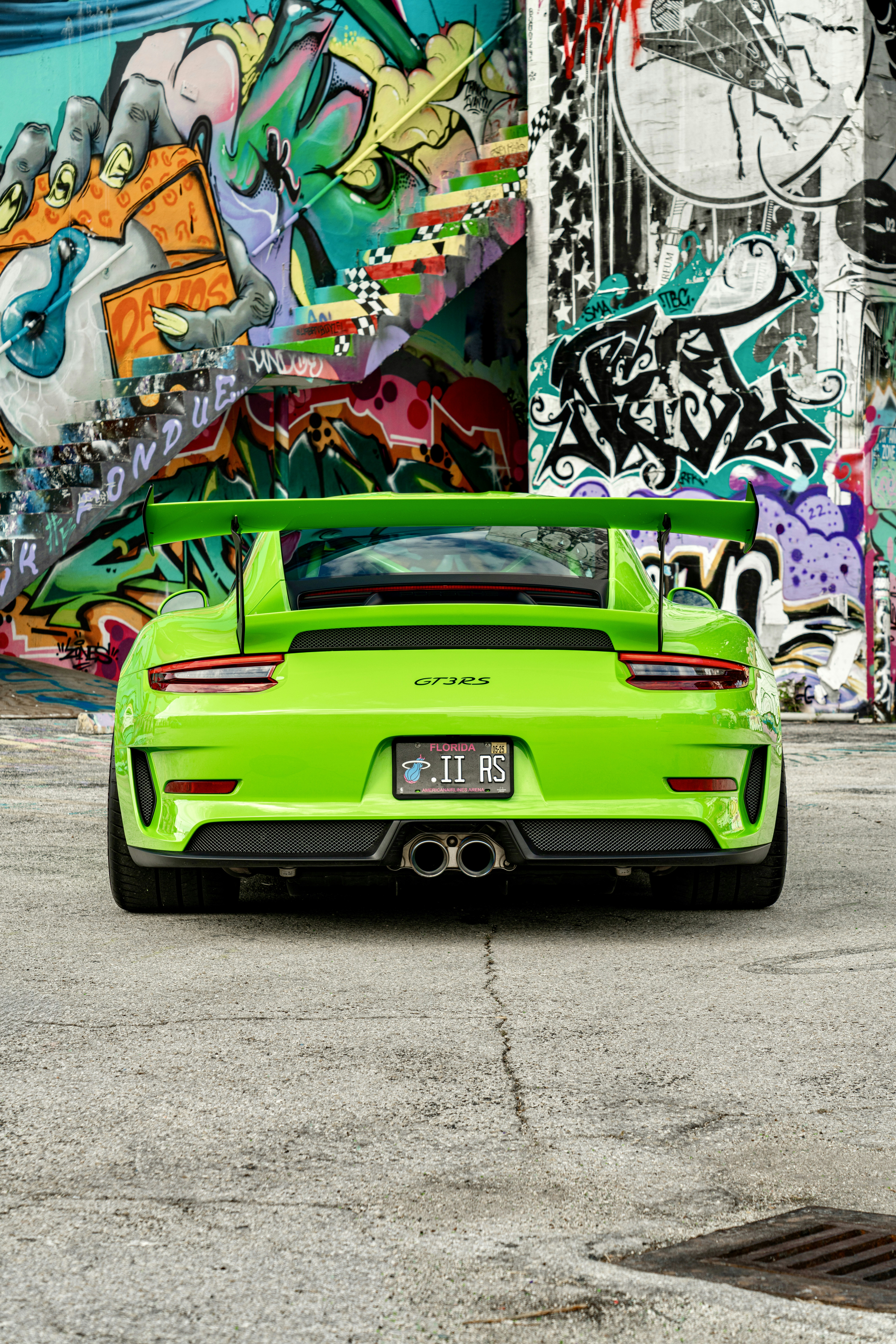 A green sports car parked in front of a graffiti covered wall