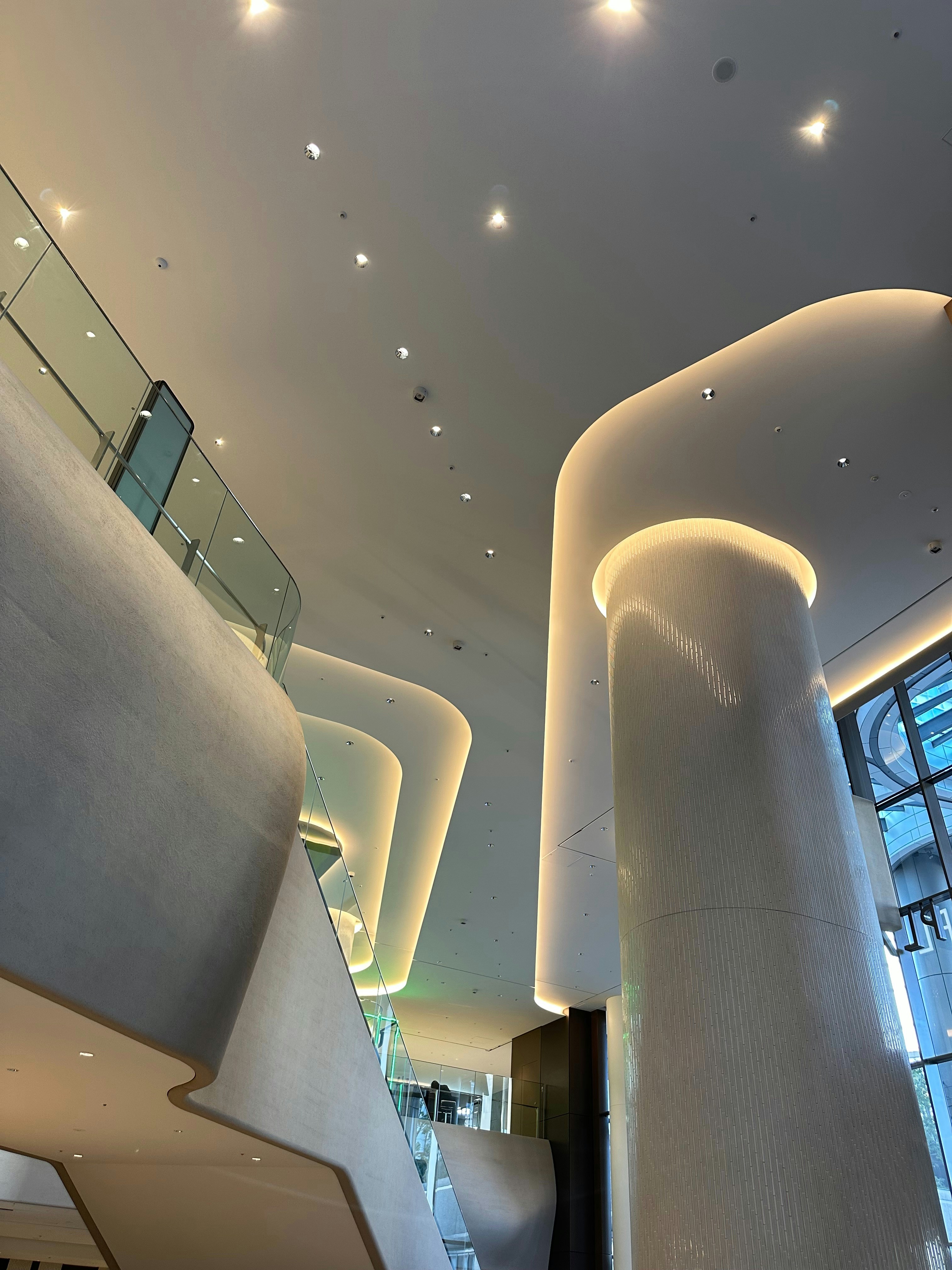 Futuristic curved interior architecture, sleek white surfaces, dramatic ambient blue-violet lighting, minimalist luxury space capsule