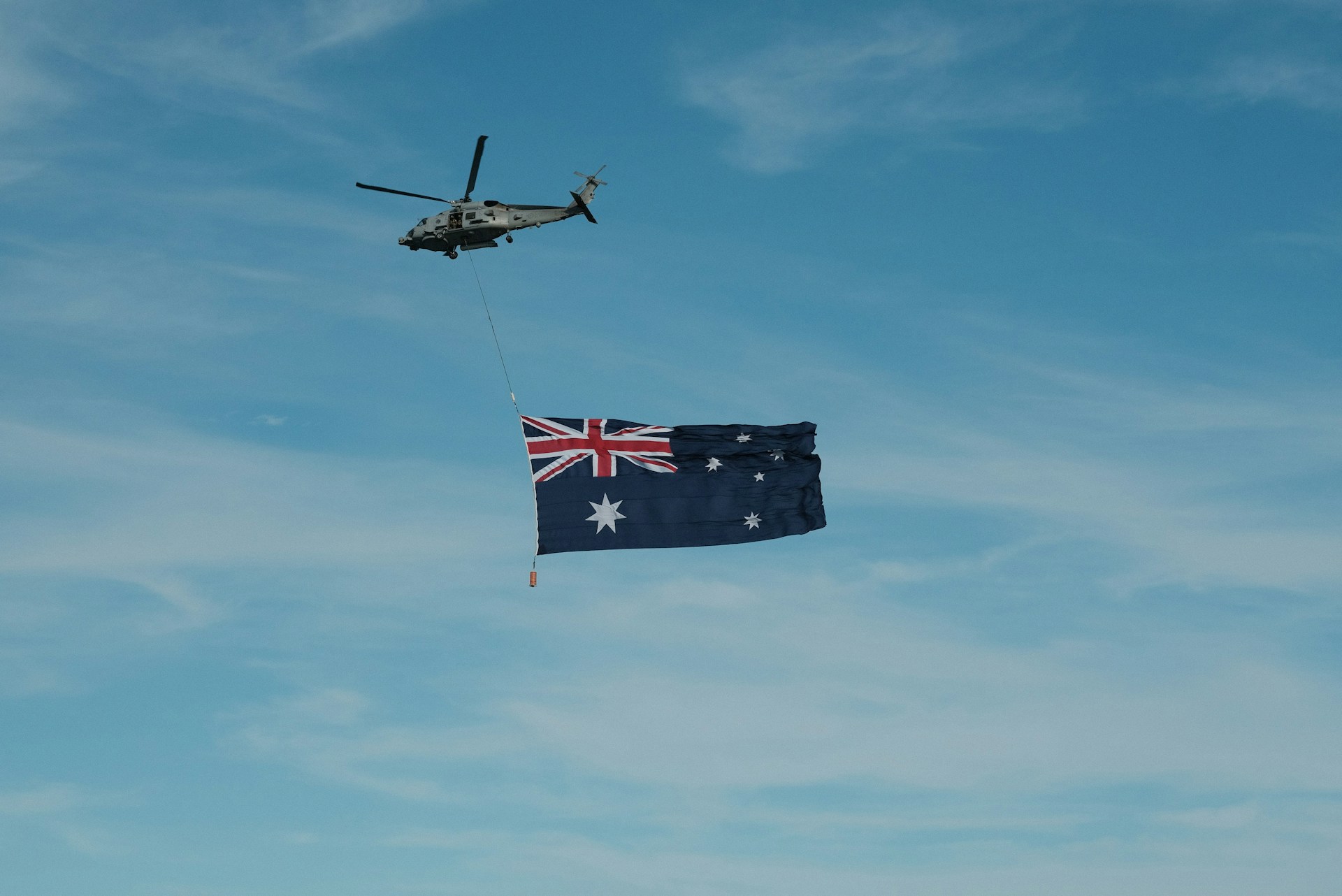 A helicopter flying next to a flag flying in the sky