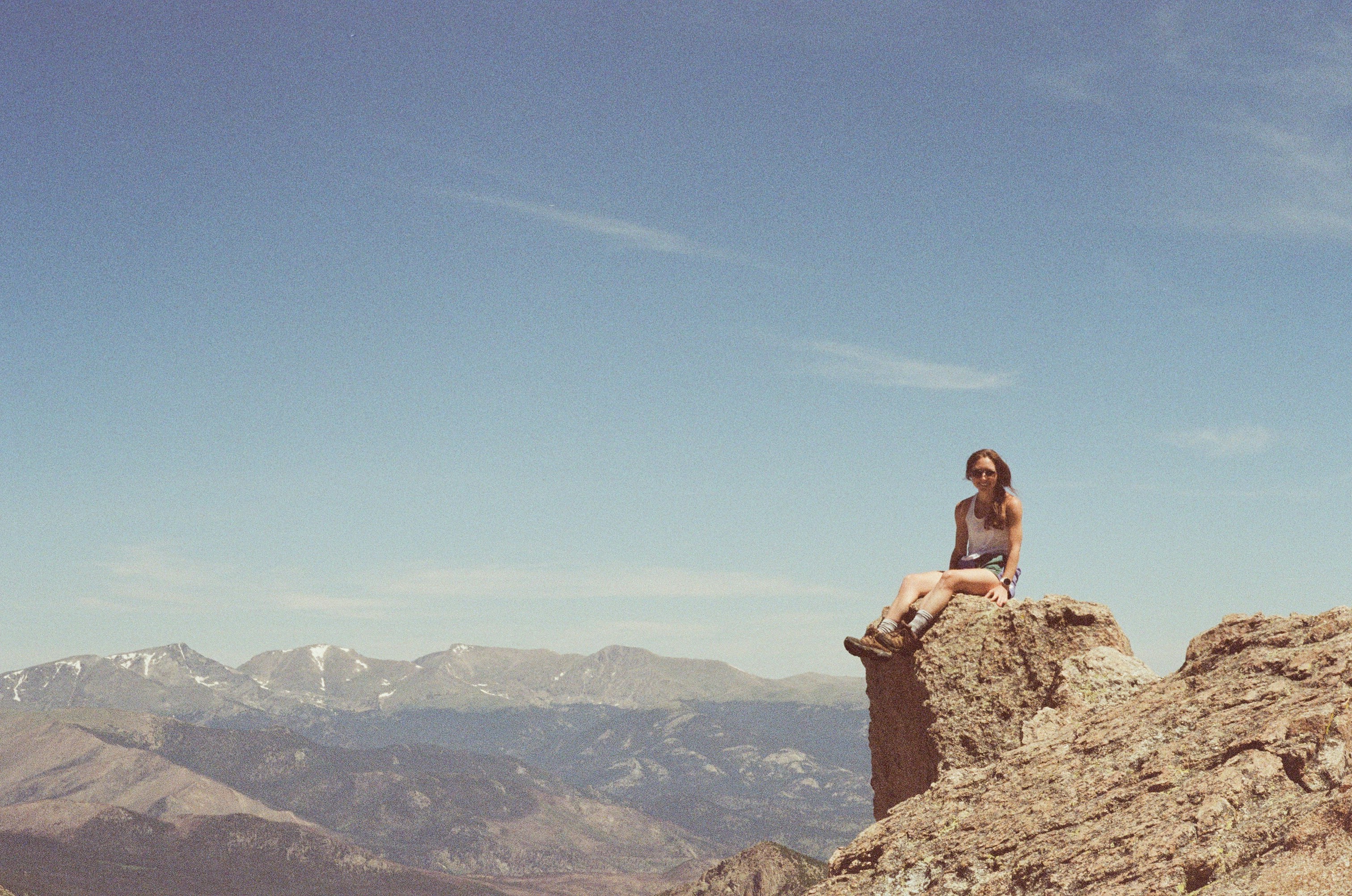 A woman sitting on top of a rocky cliff
