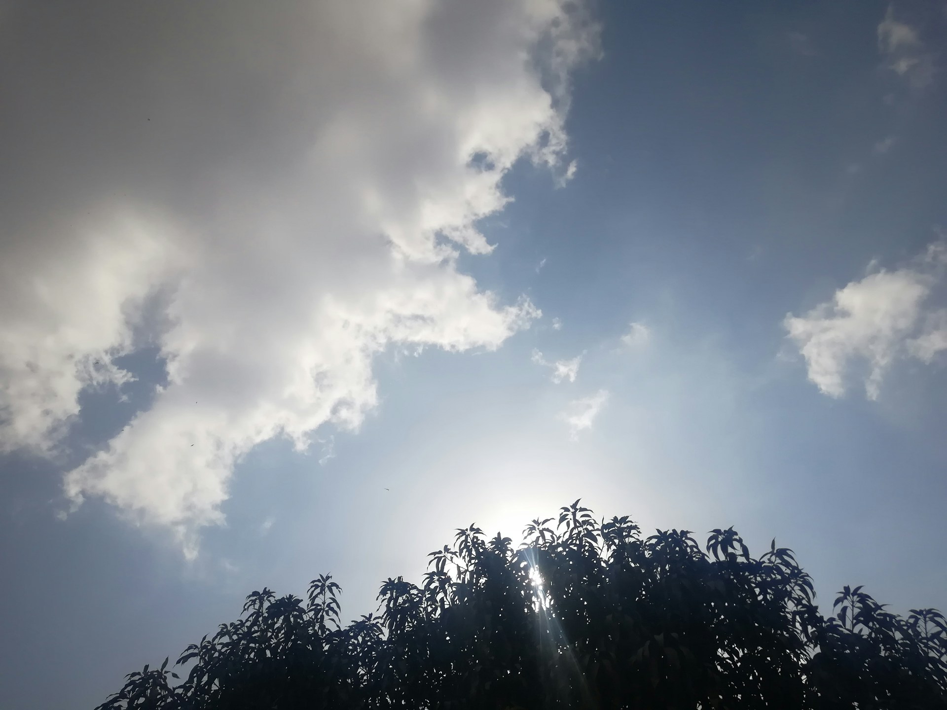 The sun is shining through the clouds in the sky