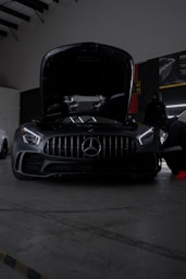 Two mercedess parked in a garage with the hood open