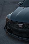 The front end of a black car parked in a parking lot