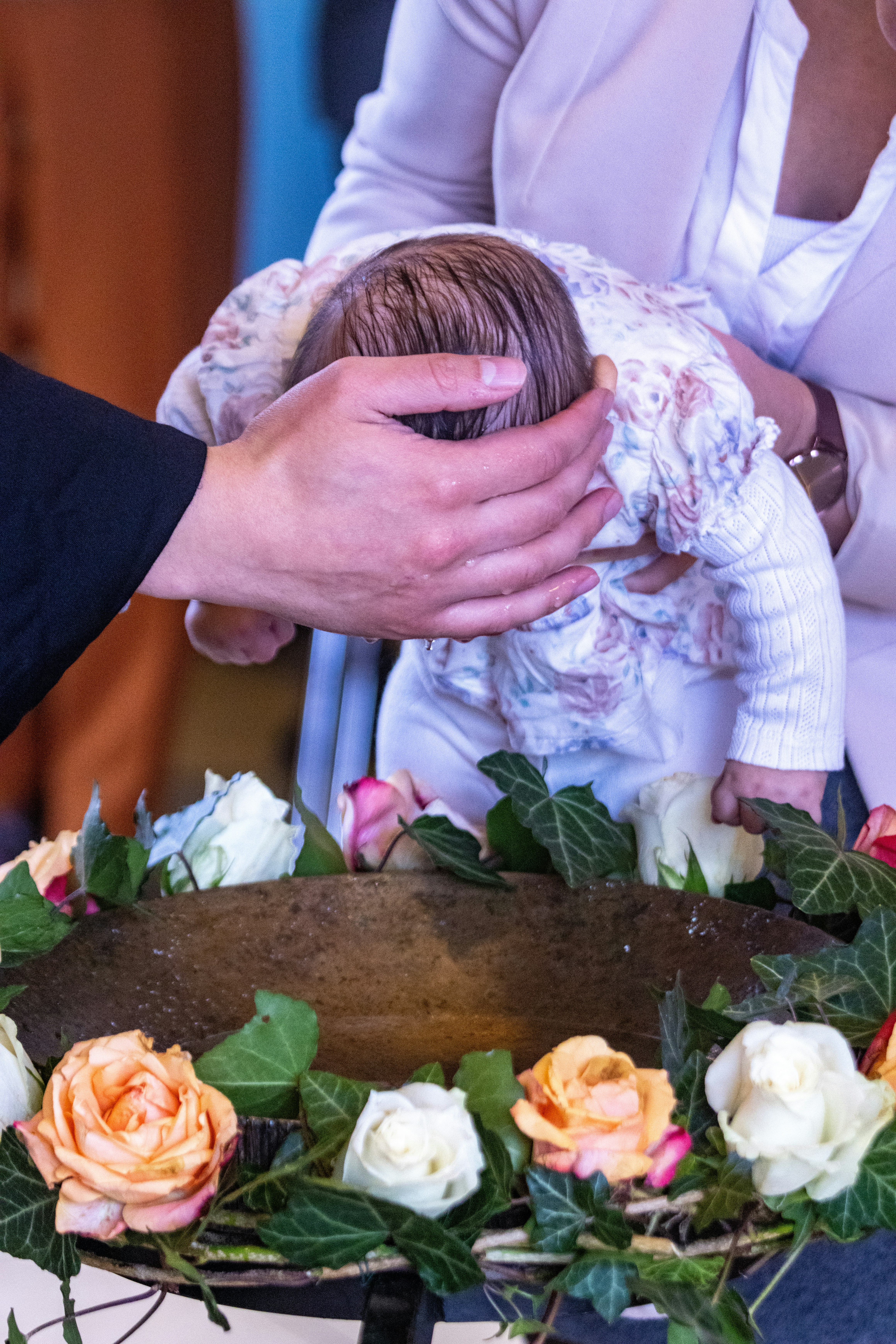 A couple of people holding a baby in front of a cake