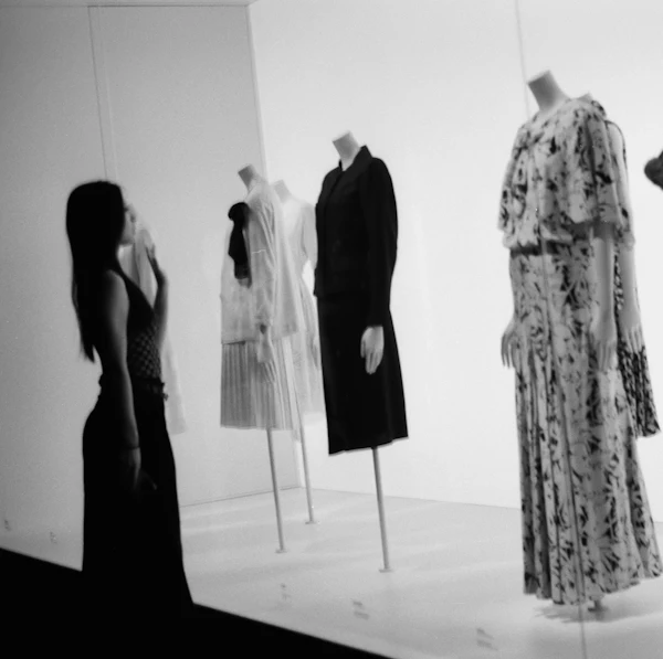 Black-and-white photograph of dress forms and mannequins displaying garments in a fashion atelier