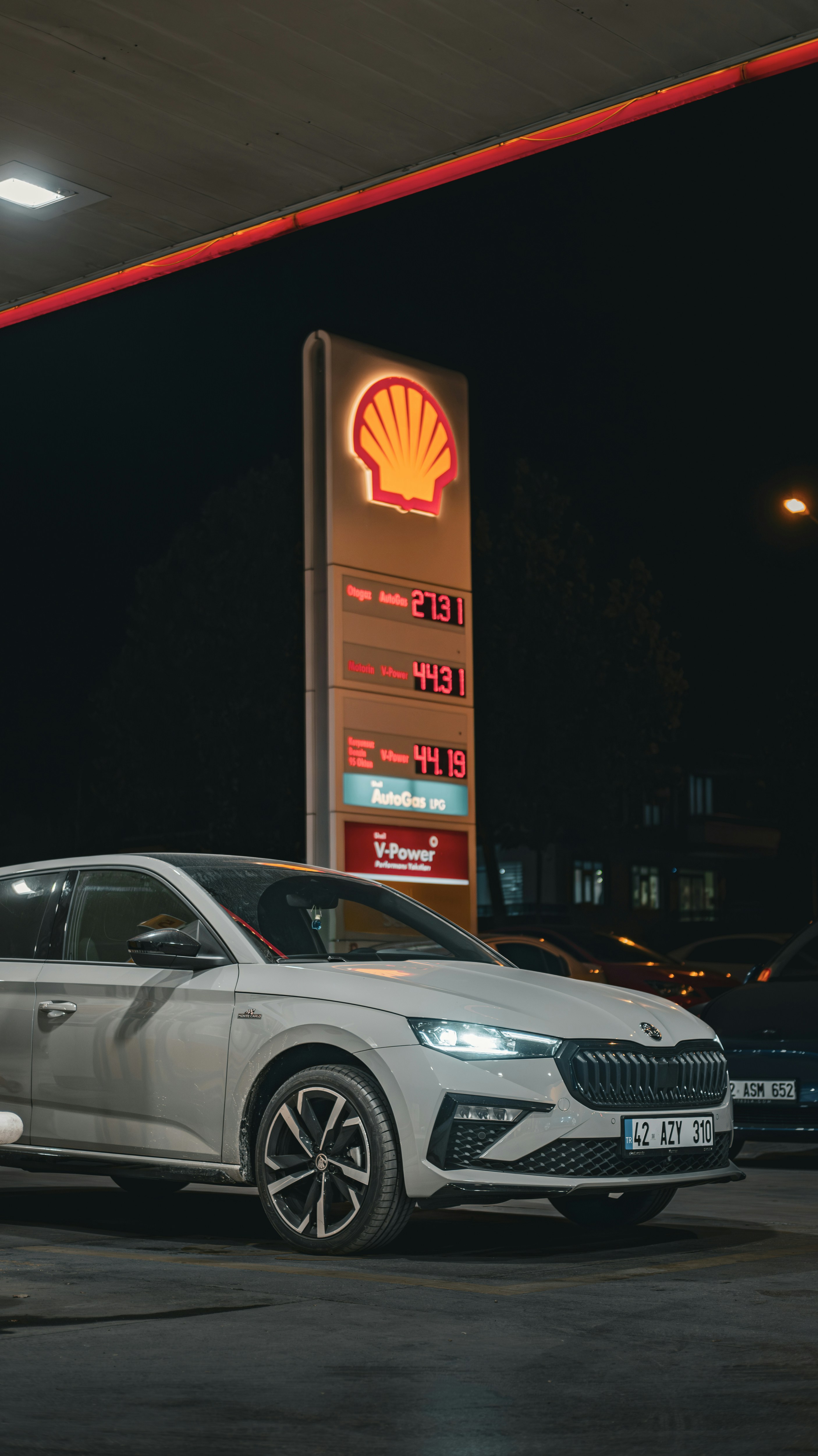 A silver car parked in front of a shell gas station