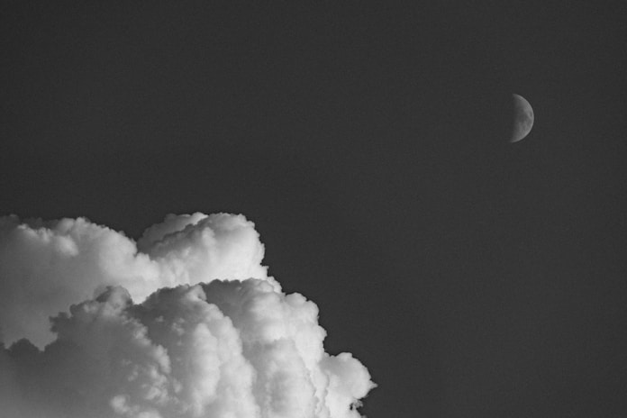 A black and white photo of the moon and clouds