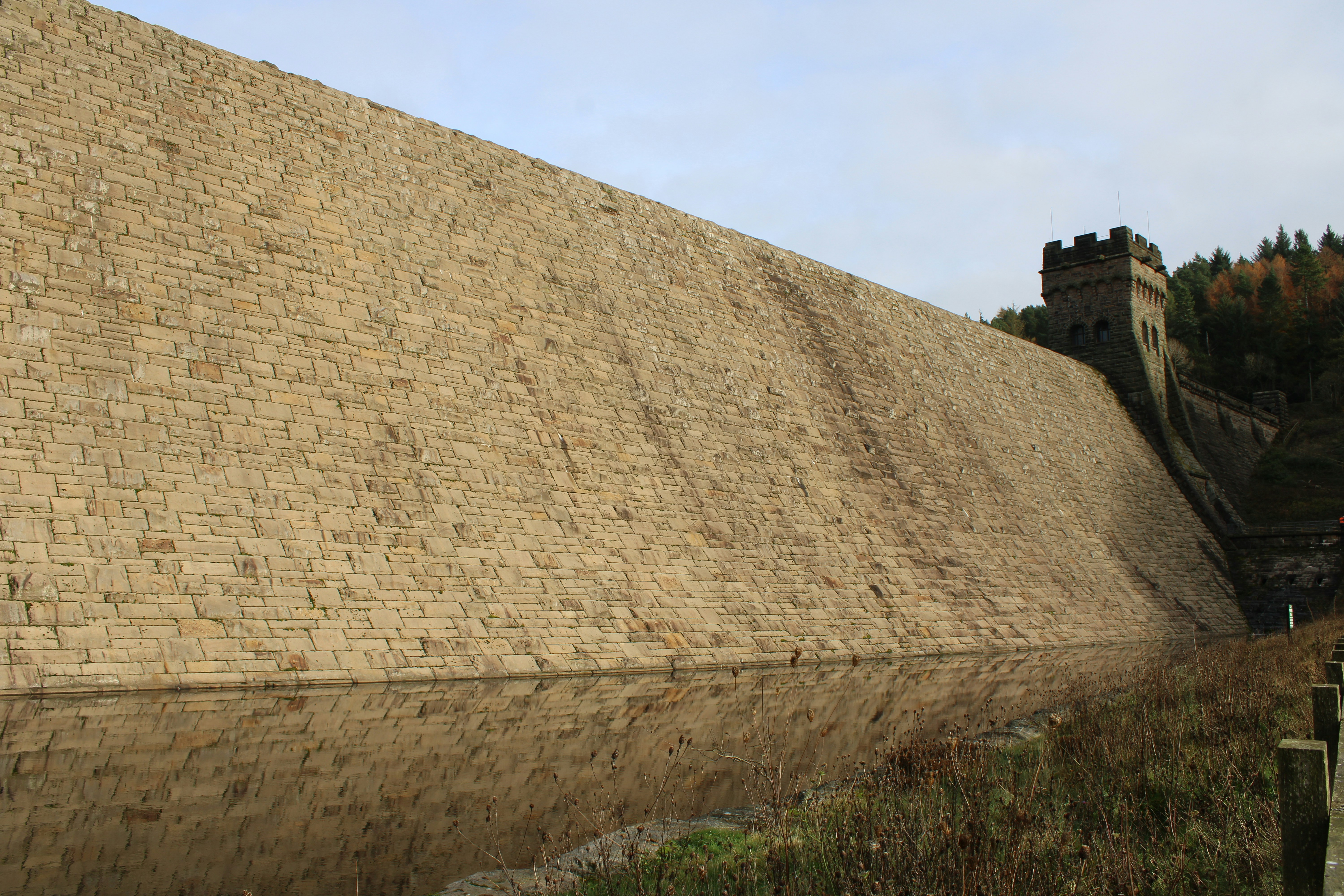 A large stone wall next to a wooden fence