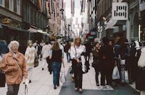 A group of people walking down a street next to tall buildings