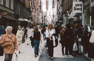 A group of people walking down a street next to tall buildings