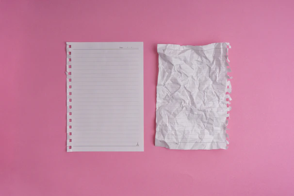 A pink wall with a notepad and a pair of scissors