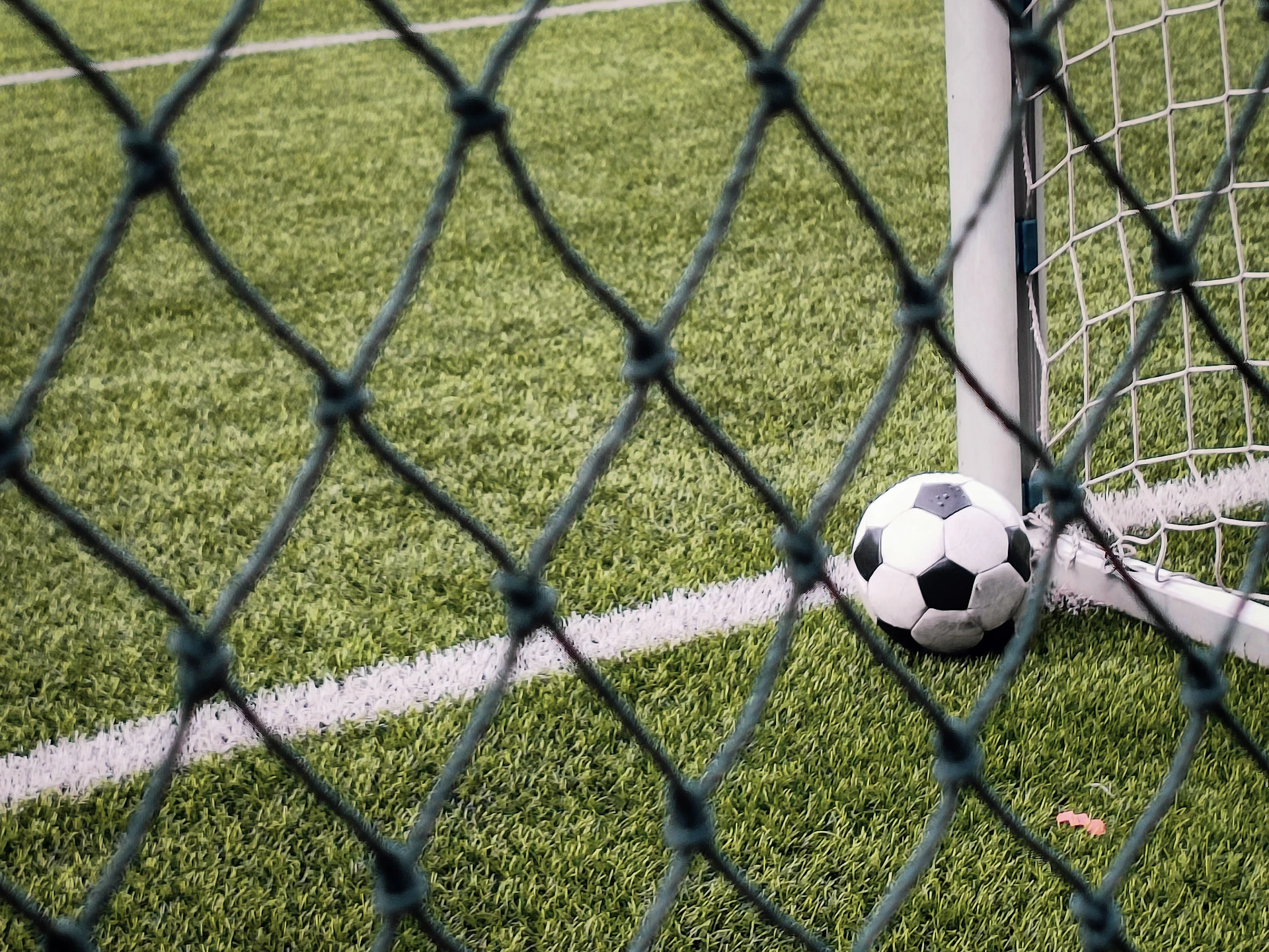 A soccer ball sitting on top of a field next to a goal