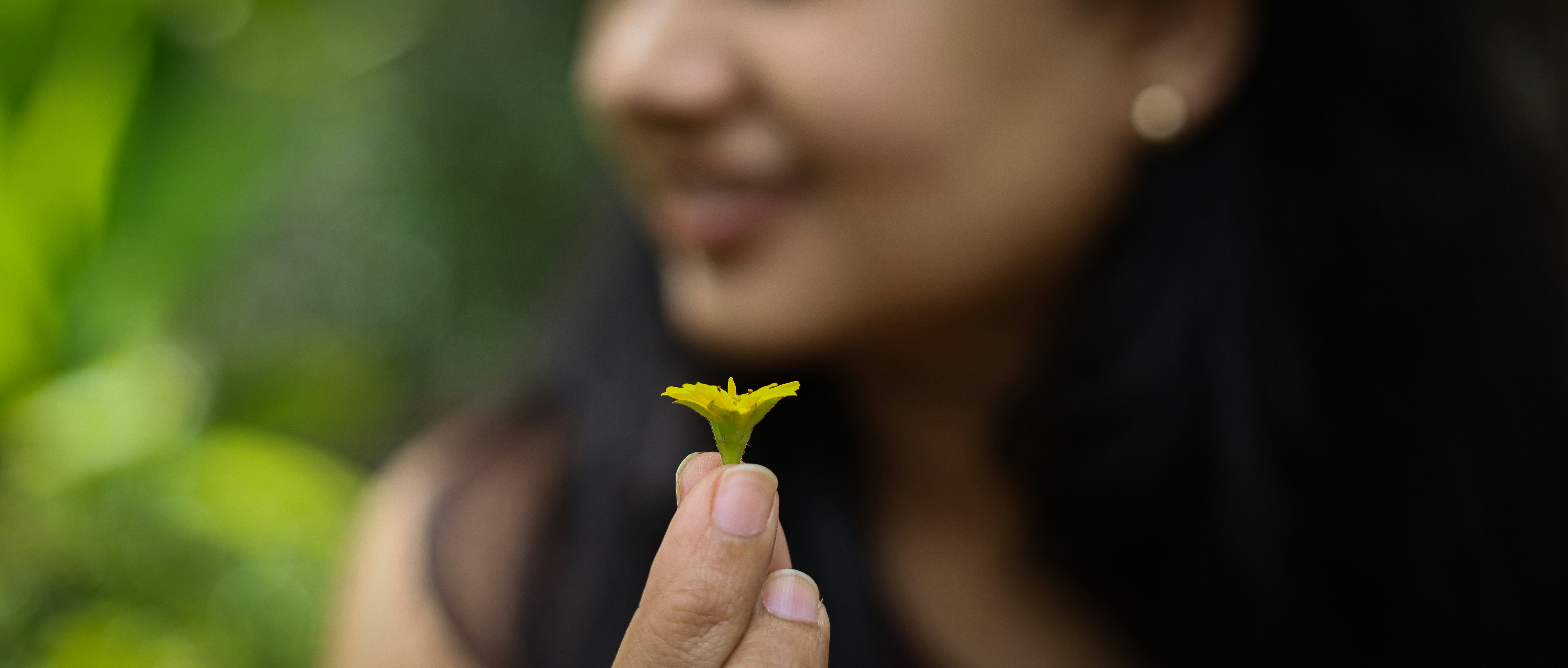 Una donna che tiene in mano un piccolo fiore giallo